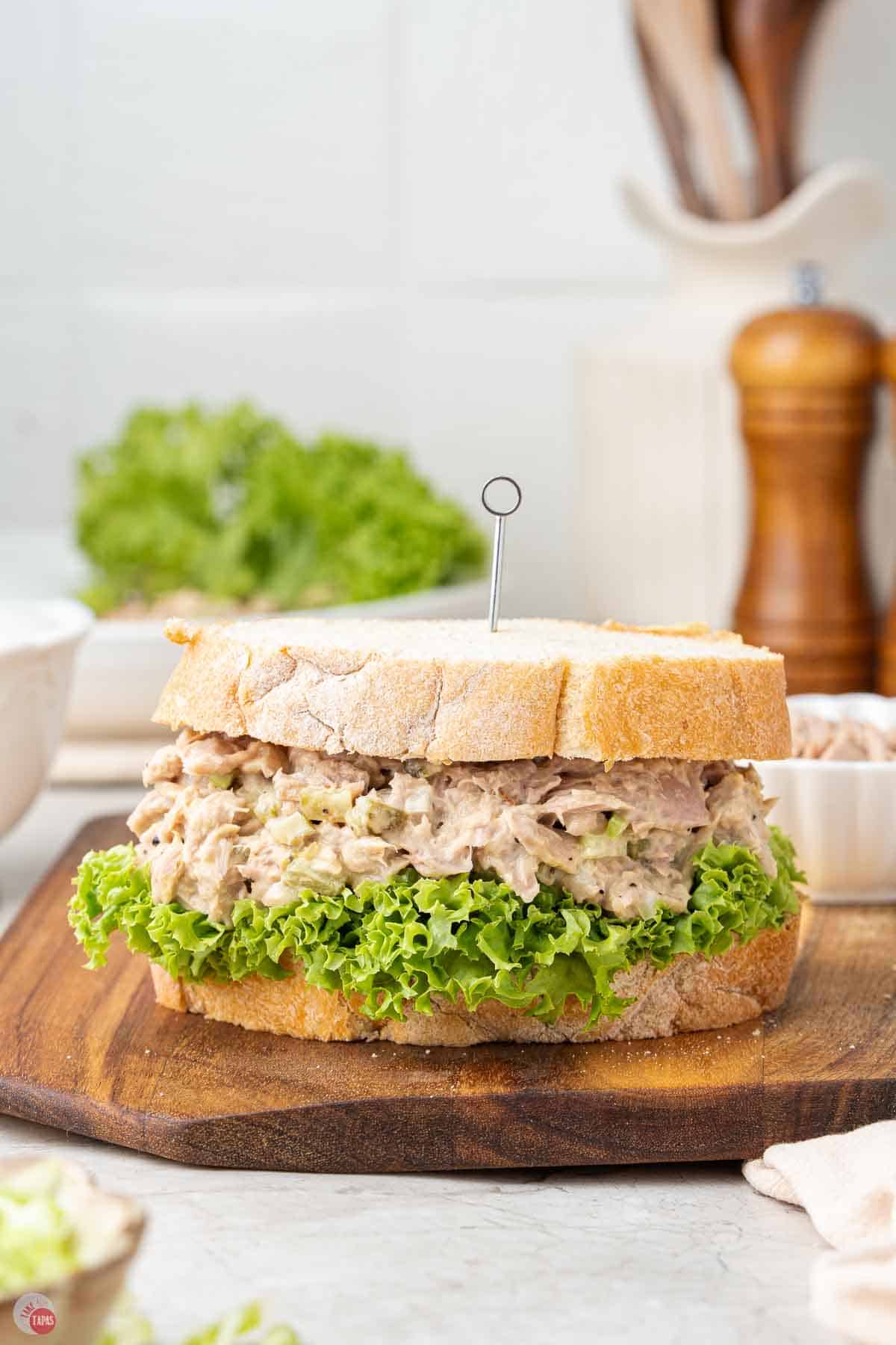 tuna salad sandwich with lettuce on a wood cutting board