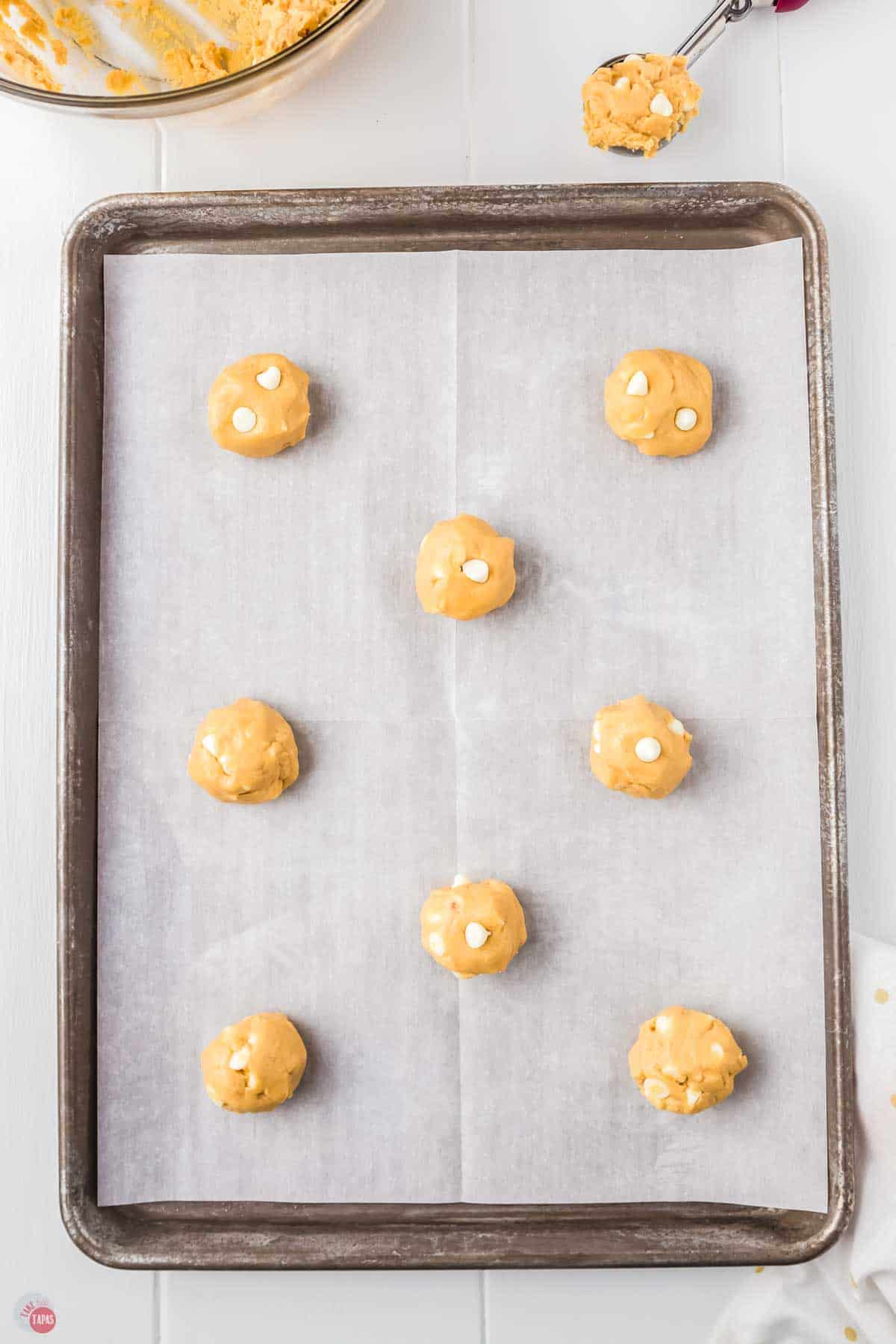 8 balls of cookie dough on a parchment lined baking sheet