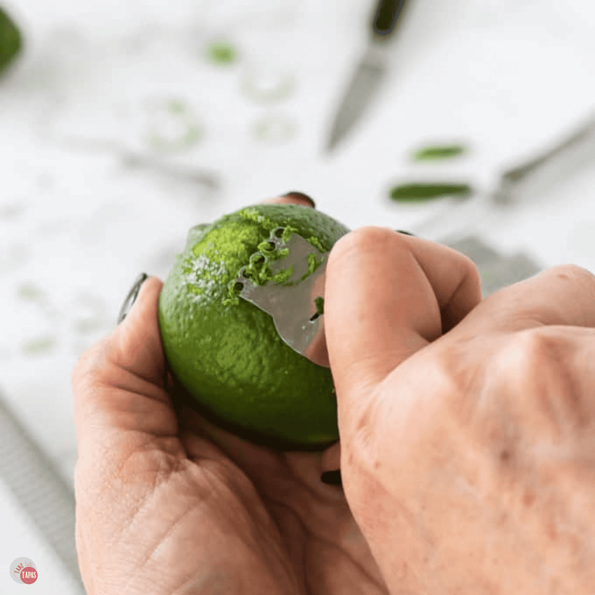 hands zesting a lime with a channel knife