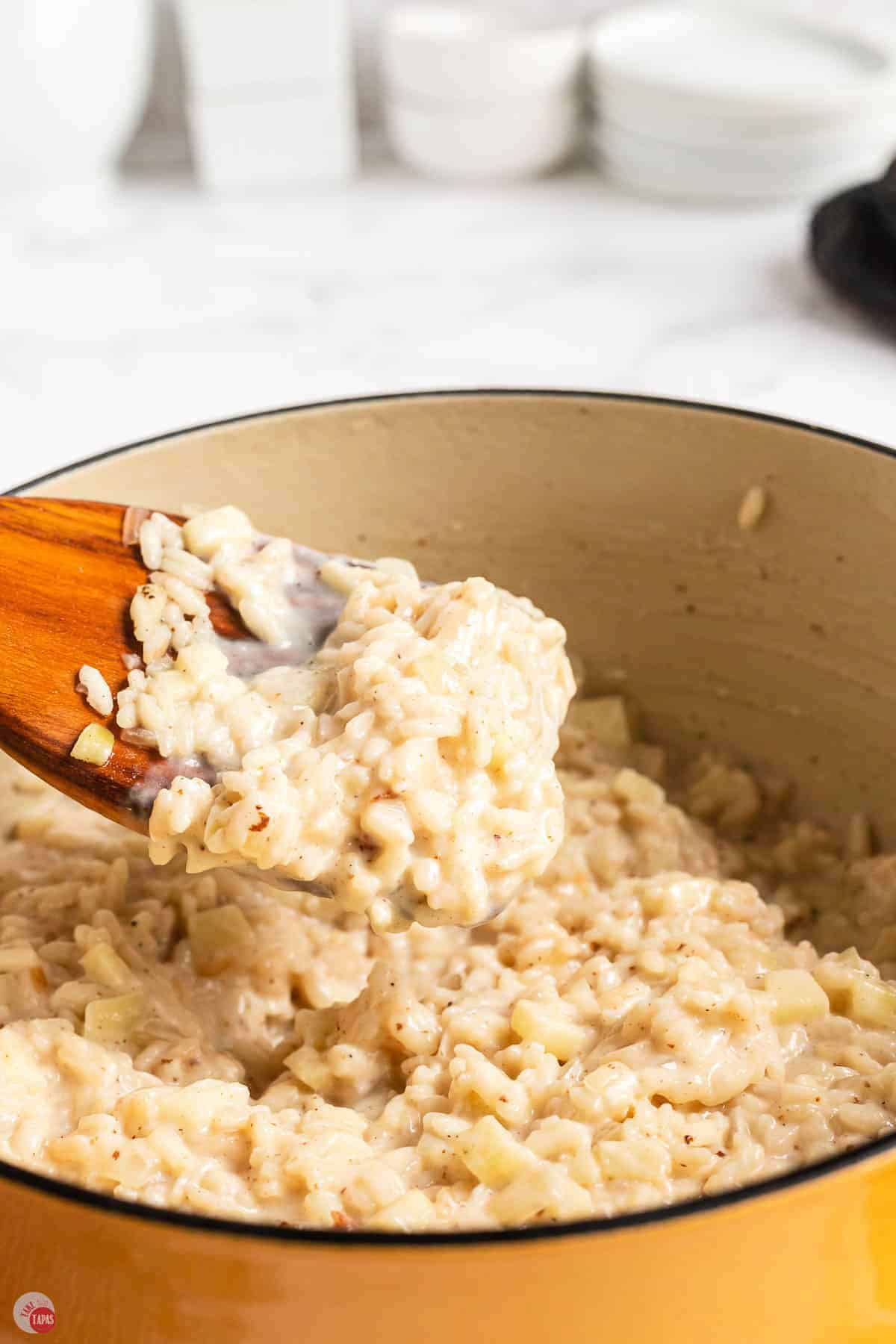 A spoonful of creamy apple risotto lifted from the pot