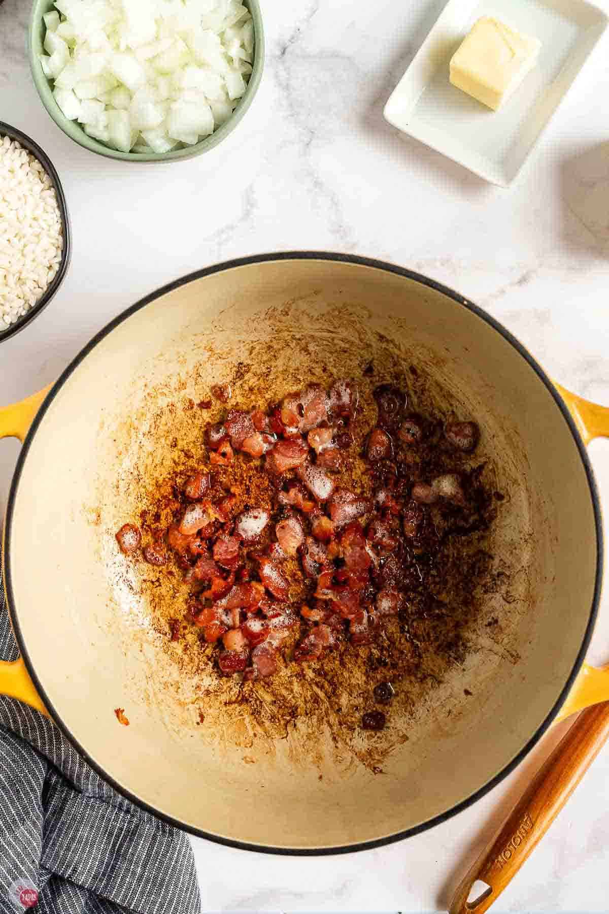 Diced bacon cooking in a yellow Dutch oven