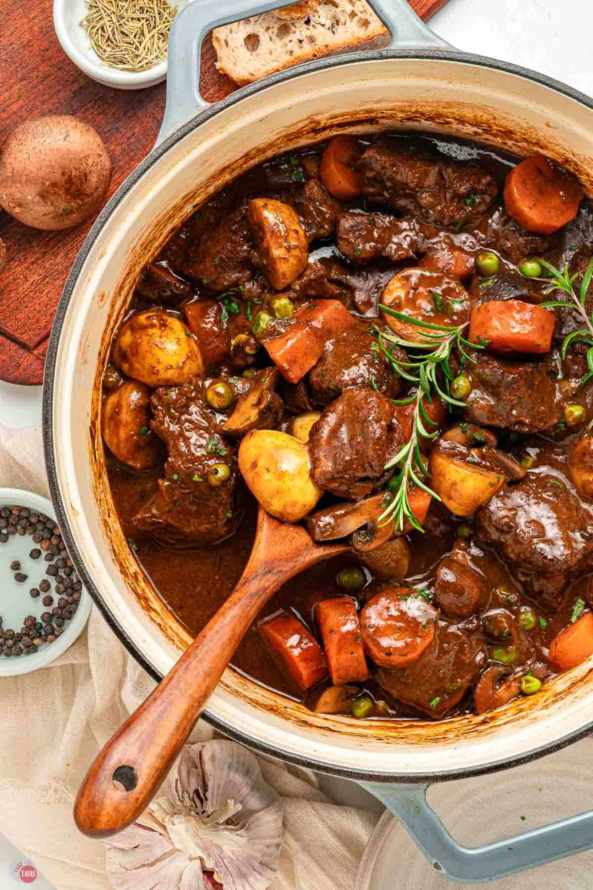 pot of beef stew with wood spoon in it