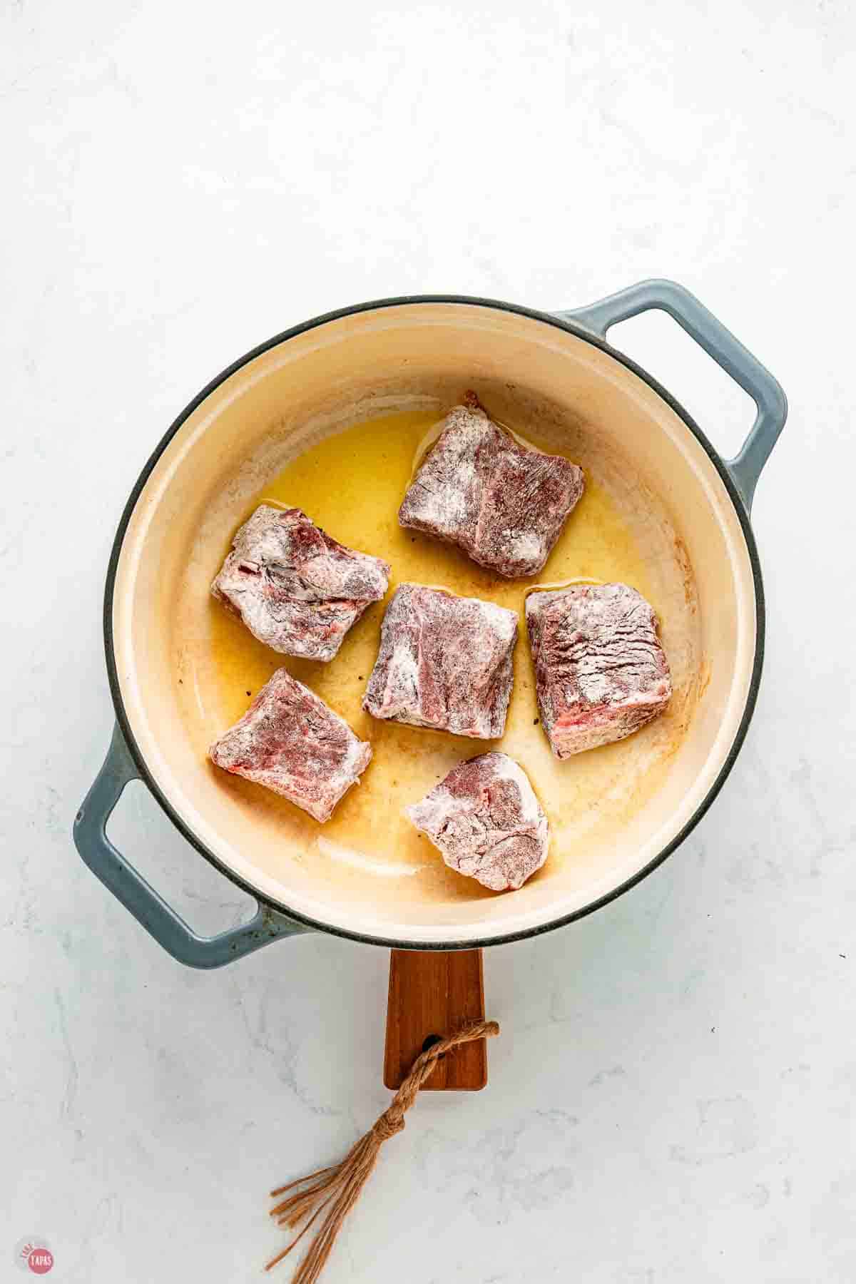 cubes of chuck roast coated in flour and searing in a pot