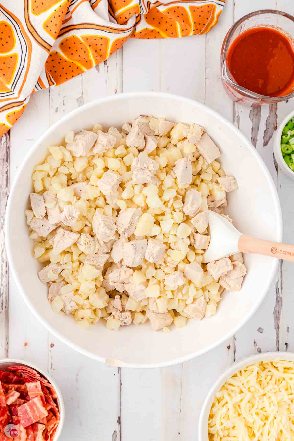 frozen potatoes and chunks of cooked chicken in a white bowl