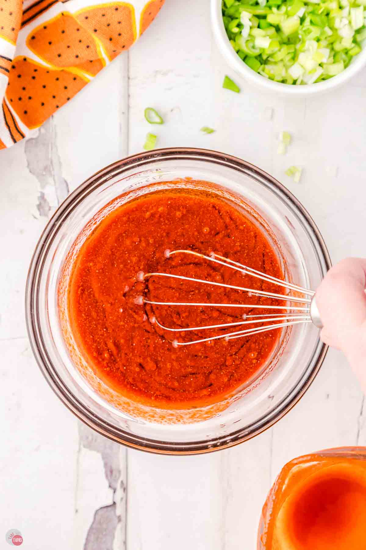 buffalo sauce being whisked in a clear mixing bowl