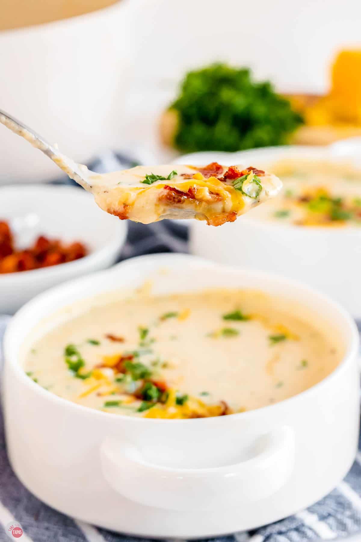 close up of spoon with soup and bacon on it