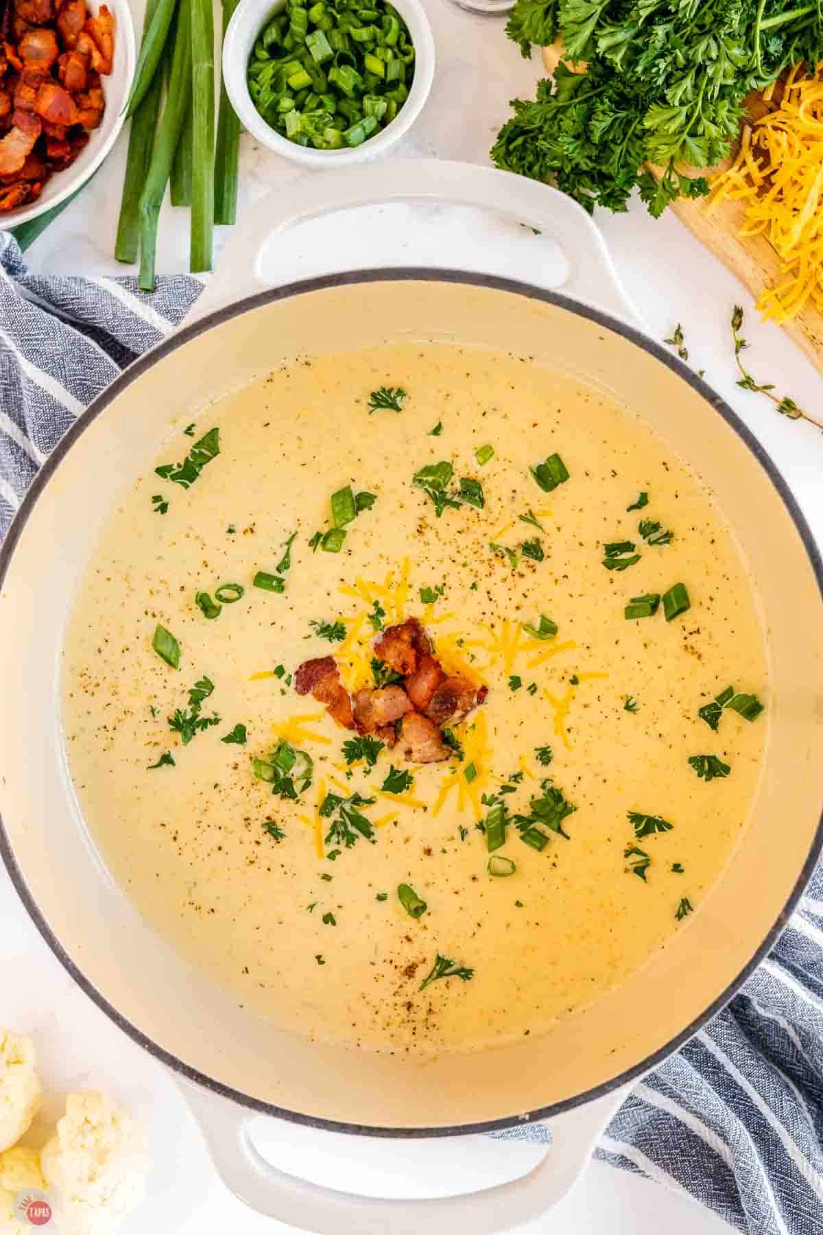 pot of cauliflower cheese soup topped with chopped parsley