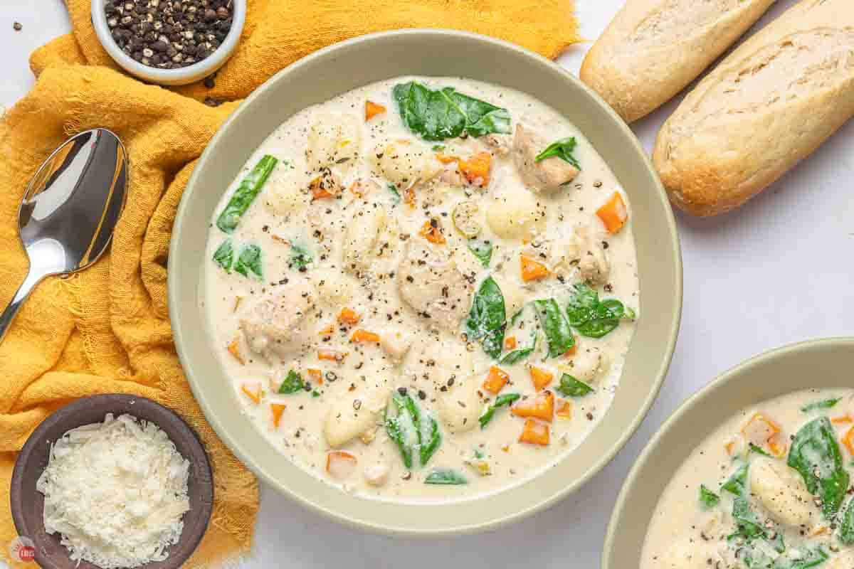 bowl of chicken gnocchi soup next to bread and a yellow napkin