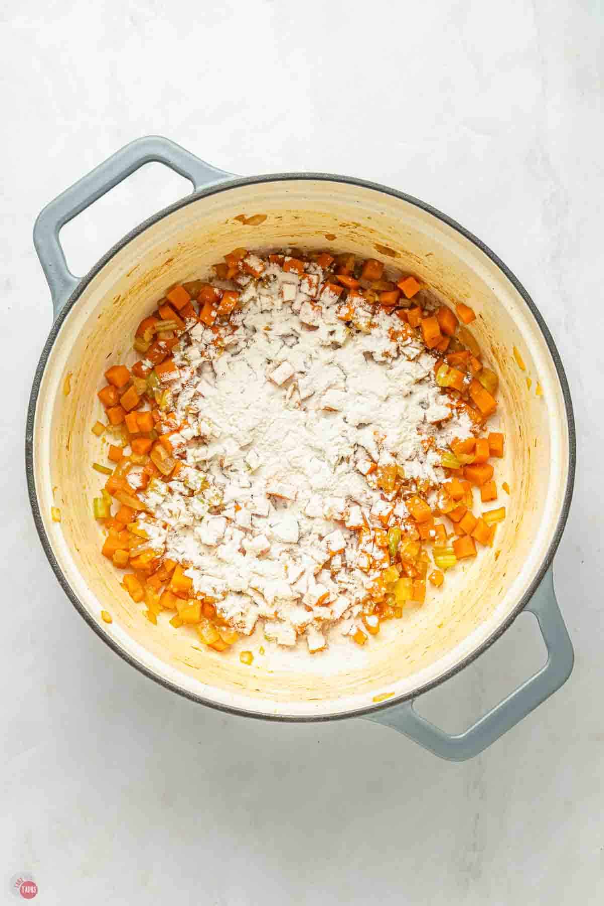 diced, cooked vegetables in a pot with flour sprinkled on top