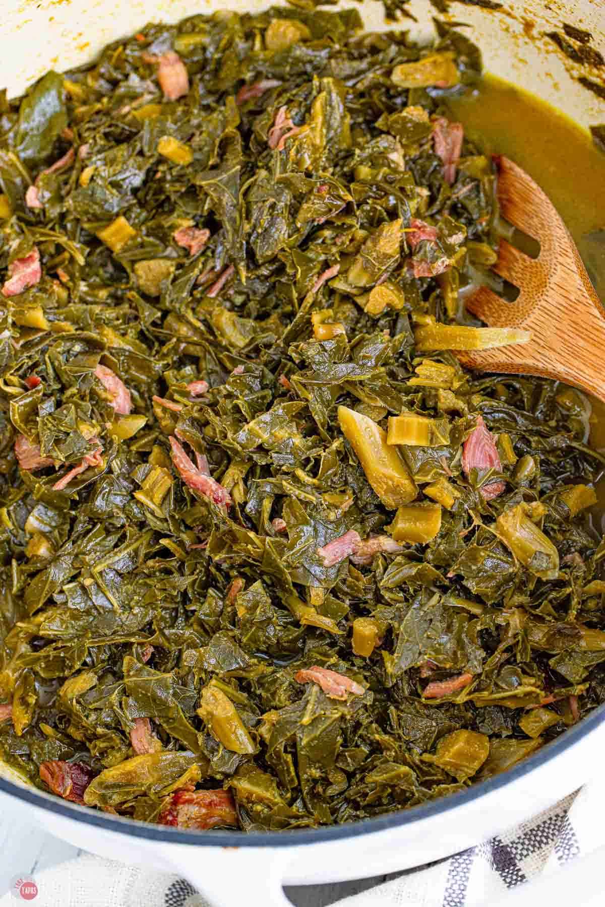 close up of collard greens in a pot with a wood spoon