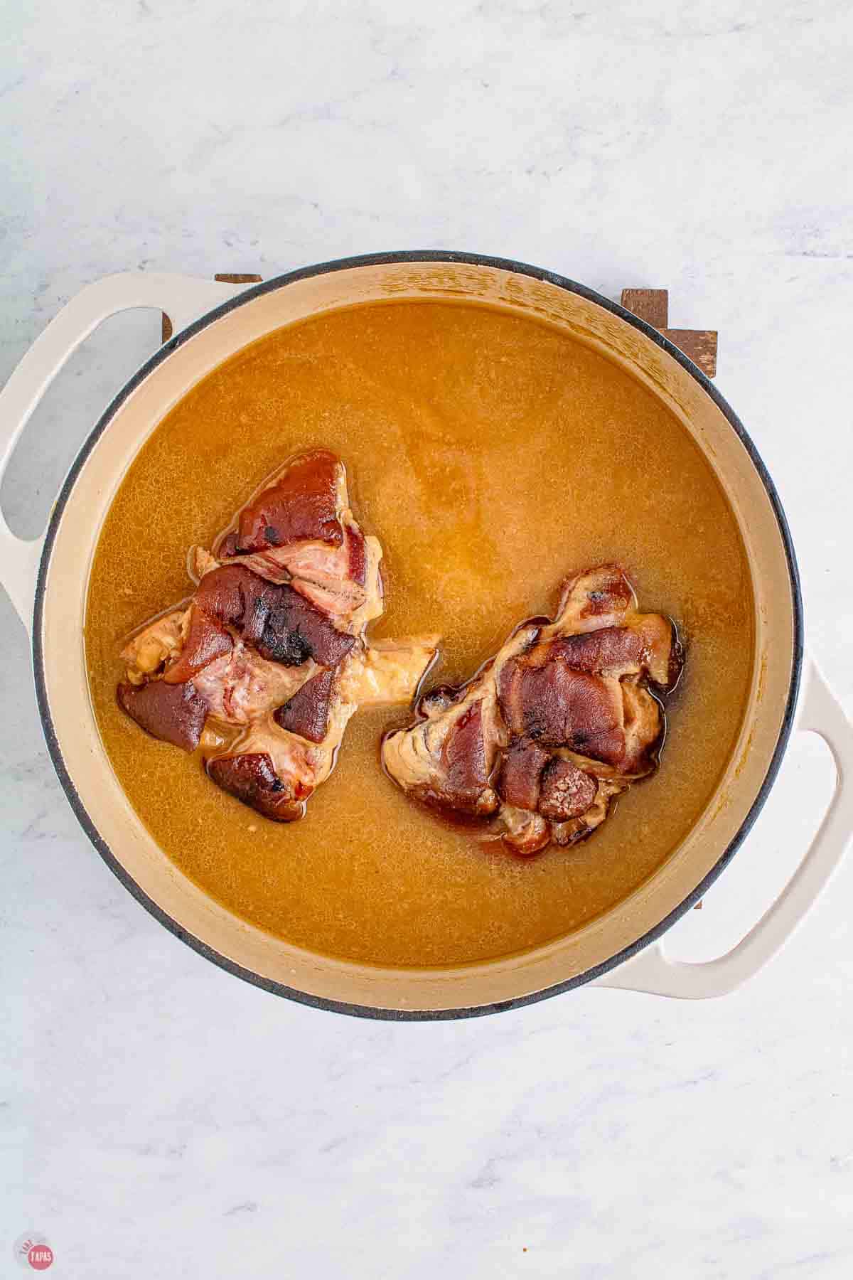 ham hocks simmering in a pot of chicken broth