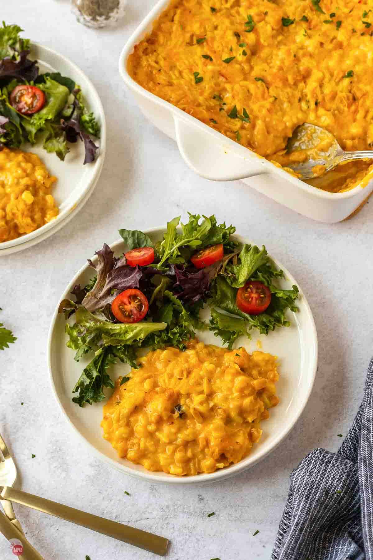 Overhead view of a plate of corn and rice casserole and green salad next to the baking dish