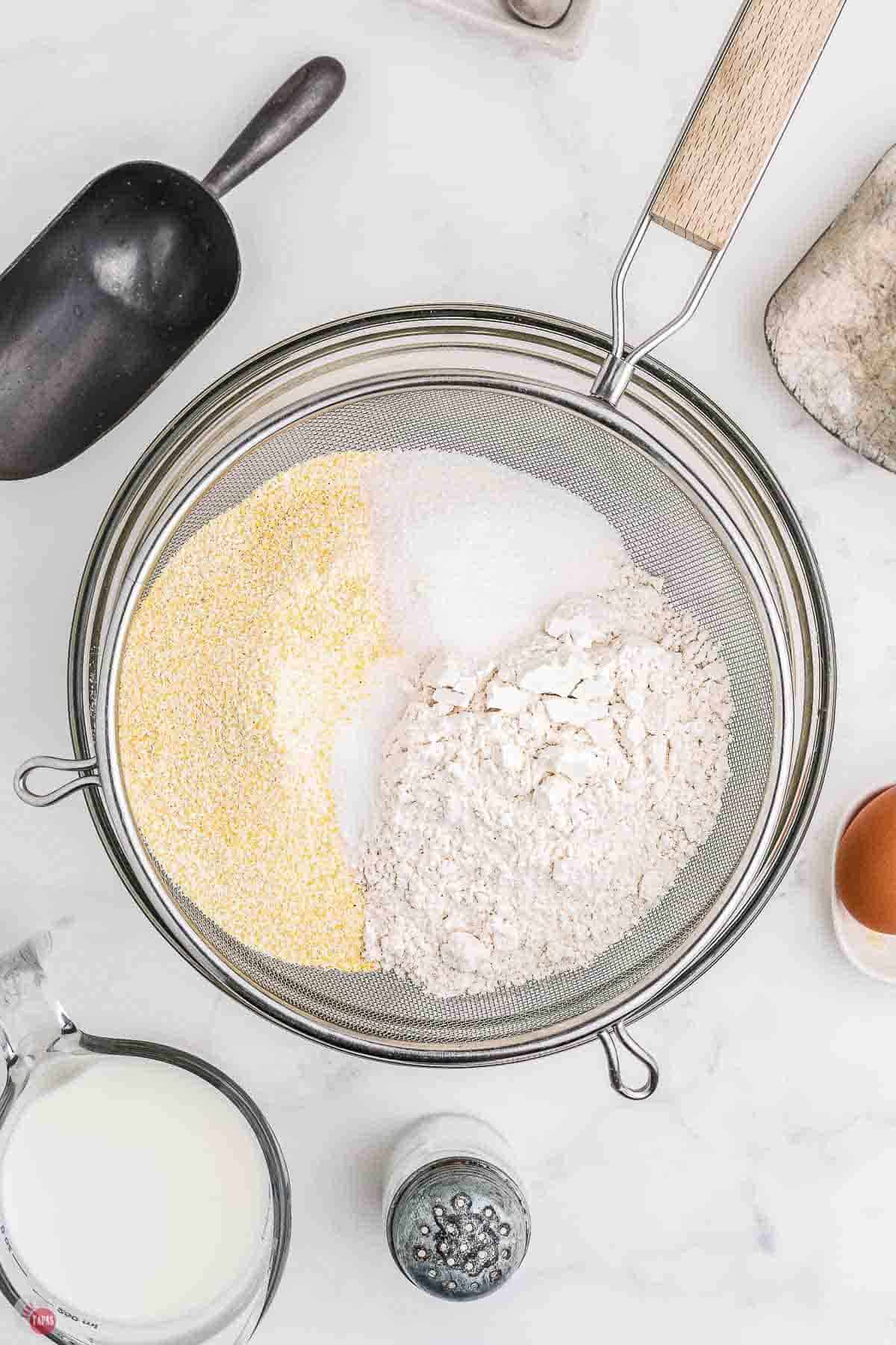 dry ingredients being sifted into a clear mixing bowl