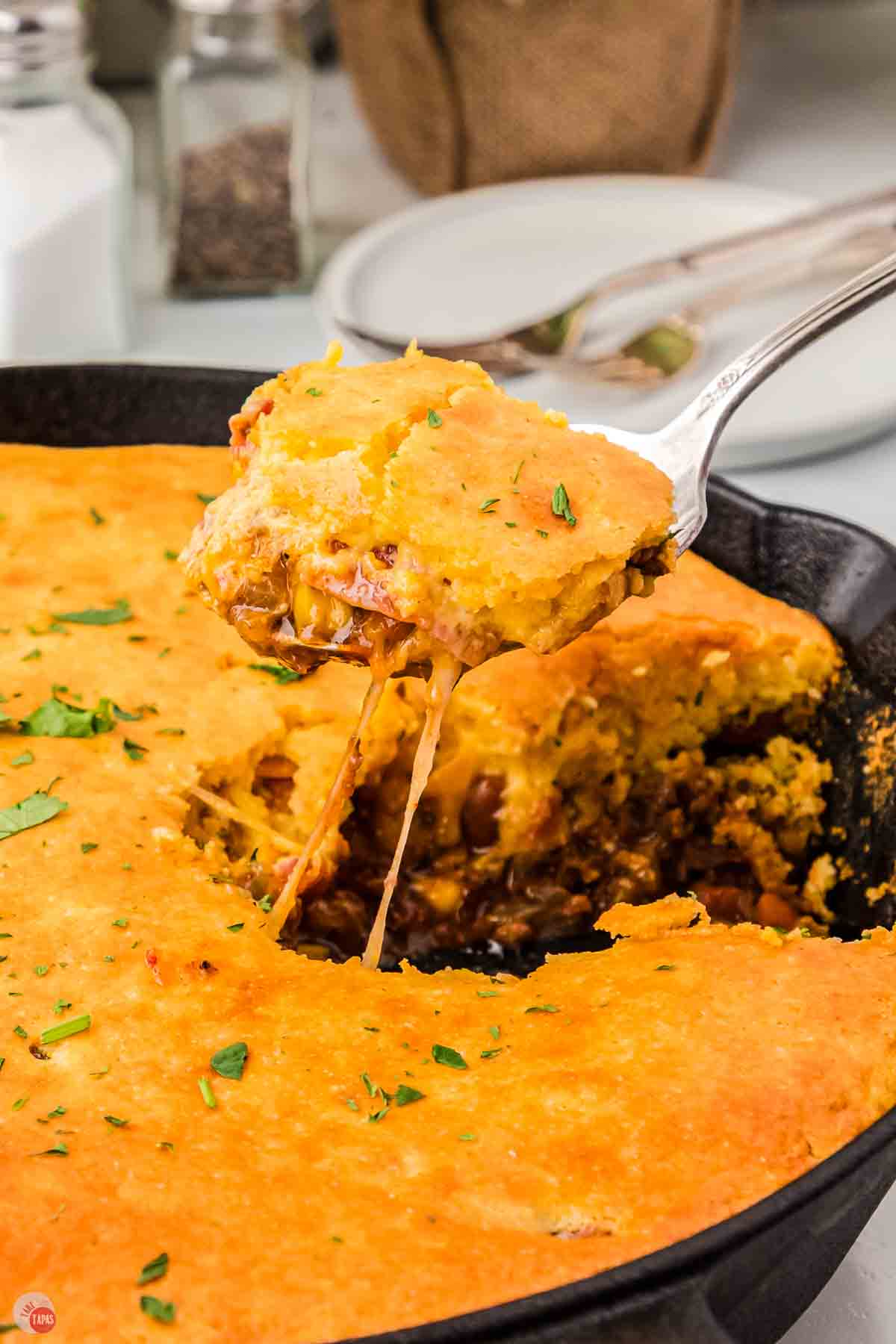 cast iron skillet with a spoon scooping out some casserole
