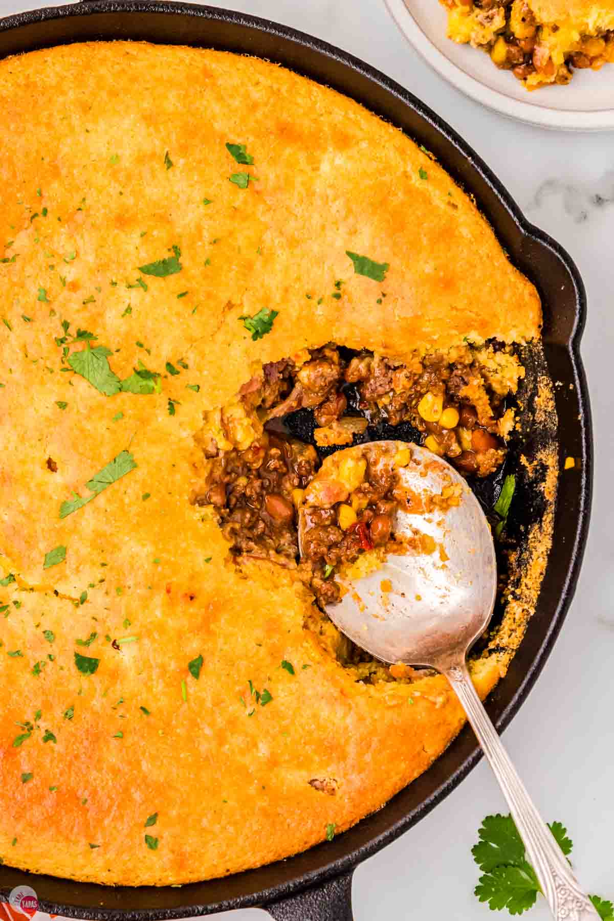 overhead view of cornbread cowboy casserole with a scoop missing and a spoon
