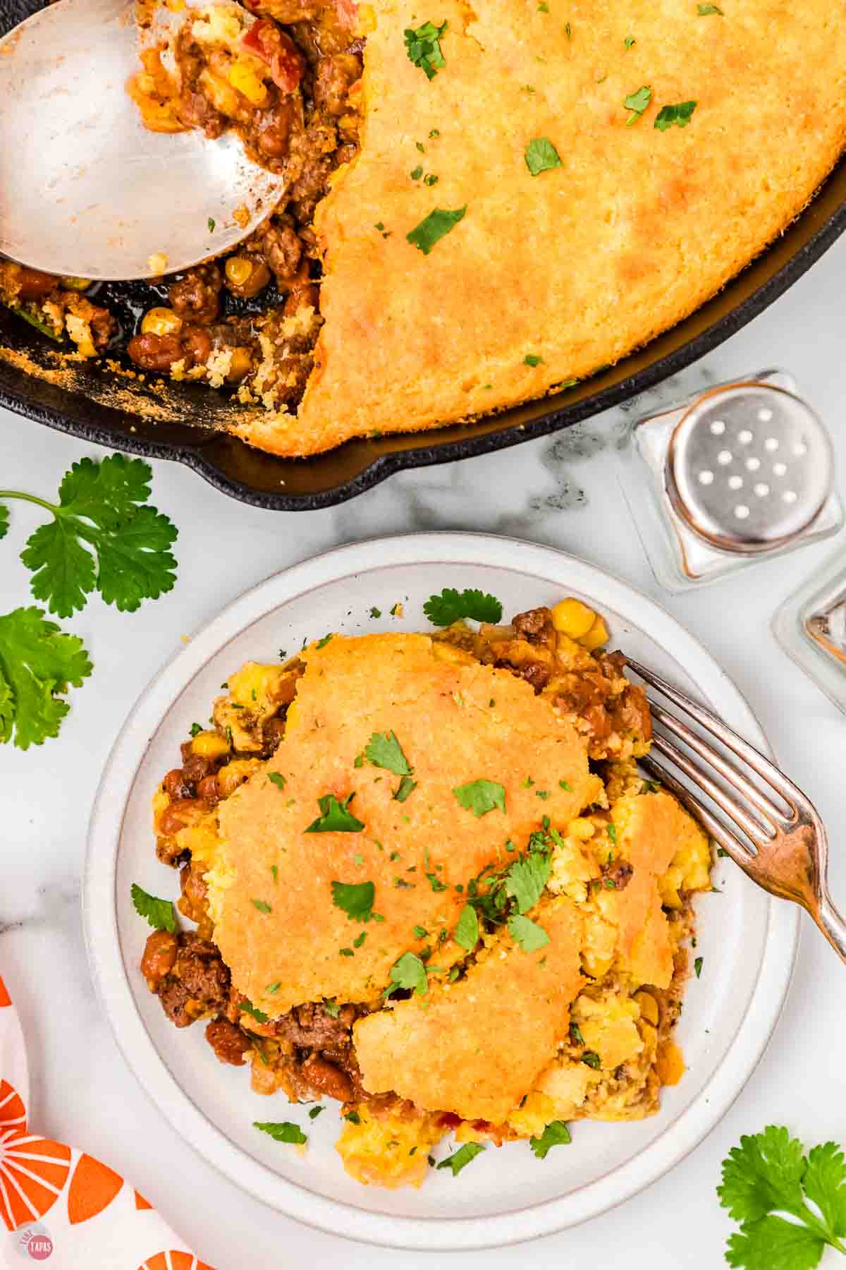 skillet of casserole with a plate and a portion on top with a fork