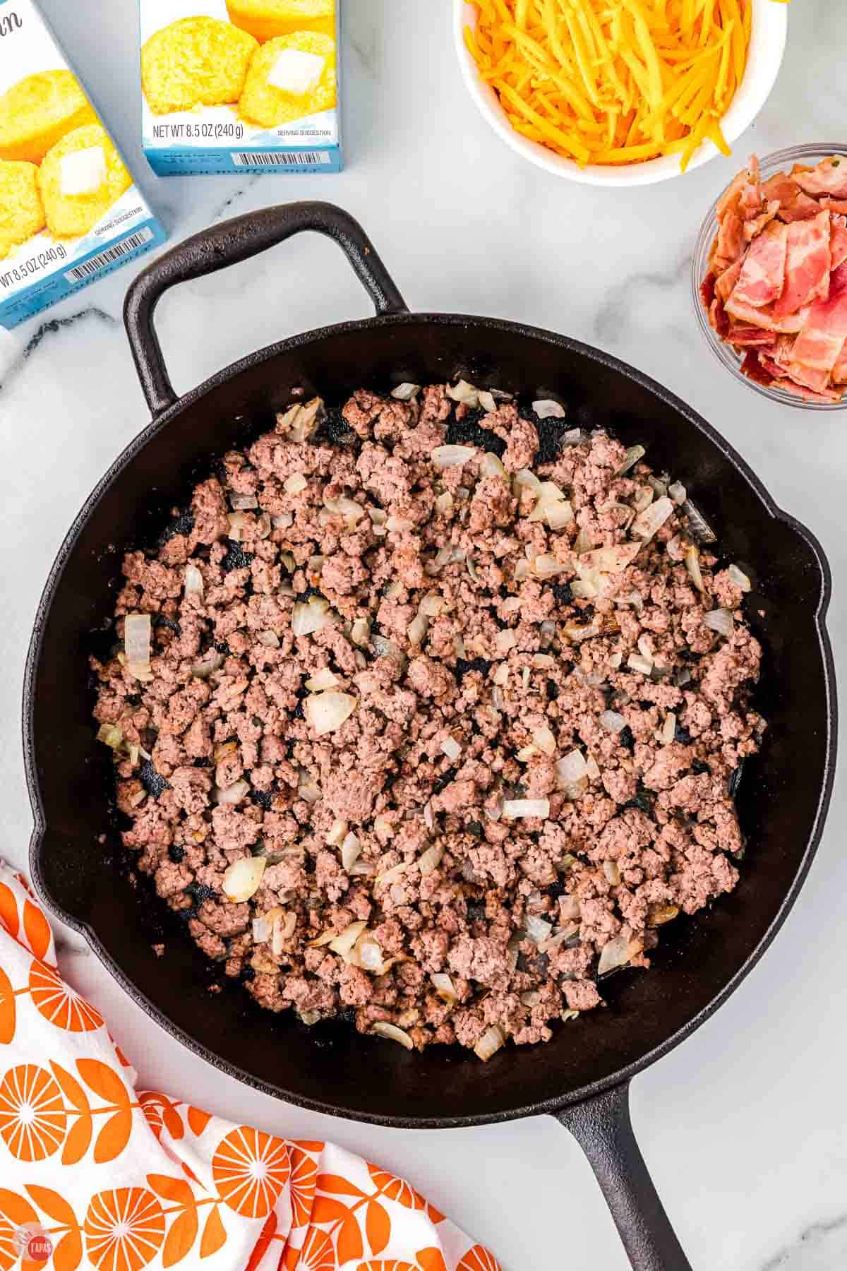ground beef and onions cooking in a cast iron skillet