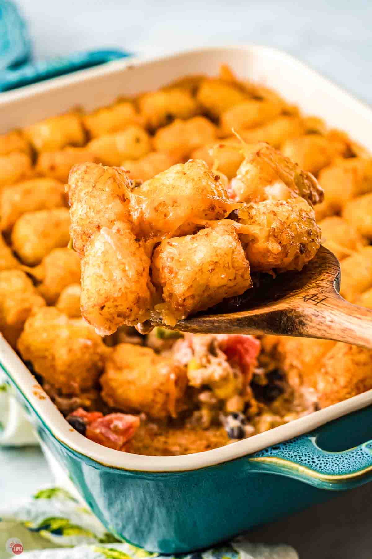 spoon scooping tater tots out of a dish