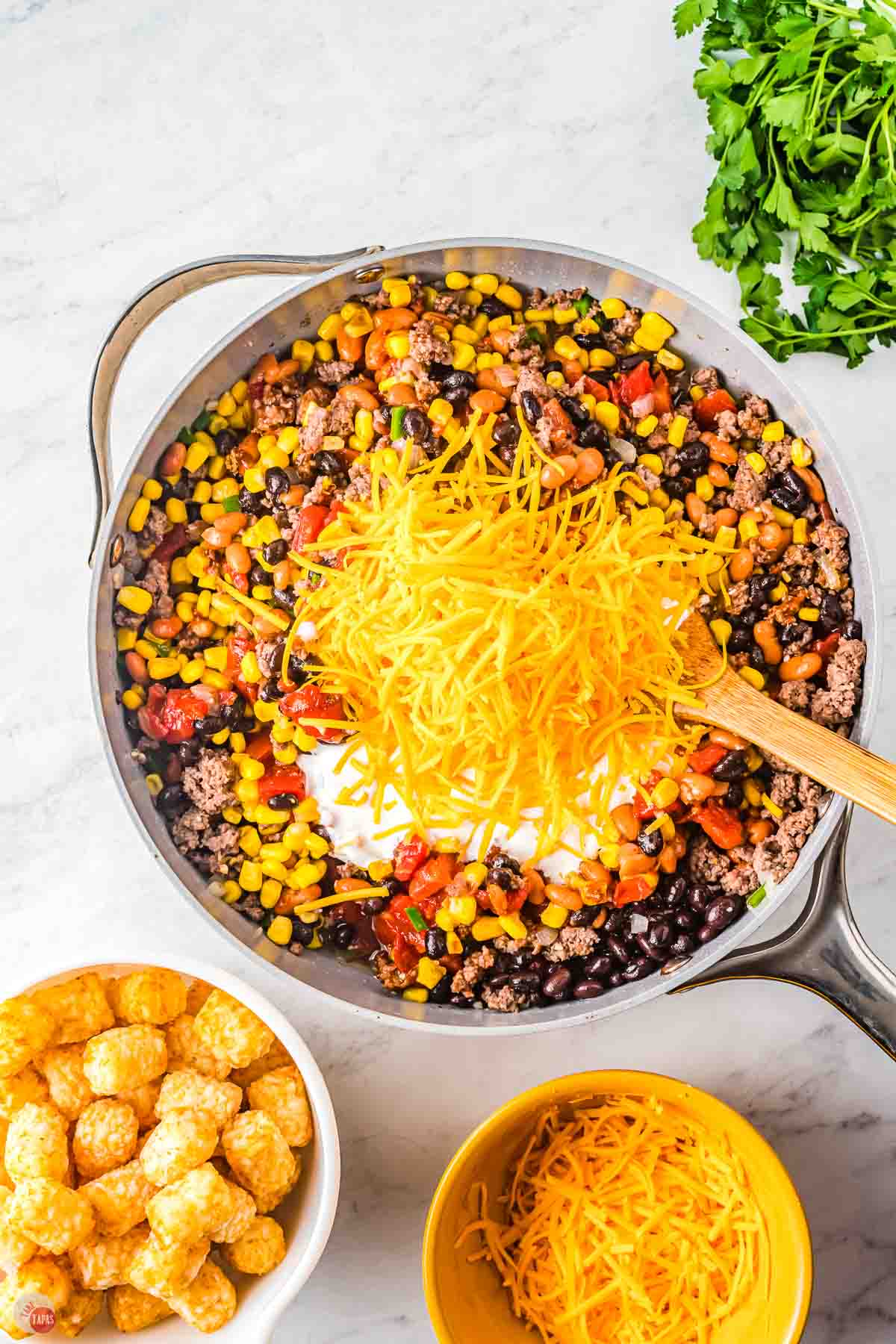 ground beef and vegetables in a skillet topped with shredded cheese
