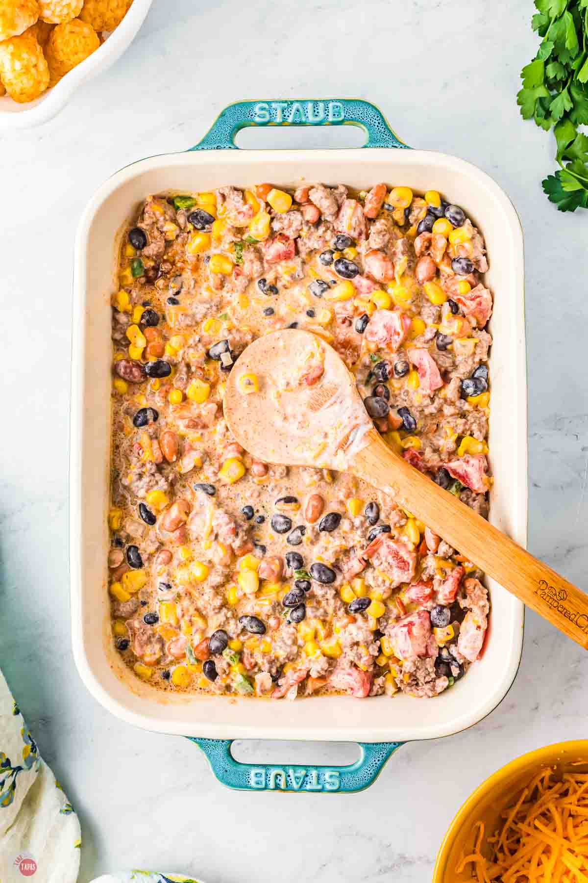 cowboy casserole mixture being spread in a baking dish