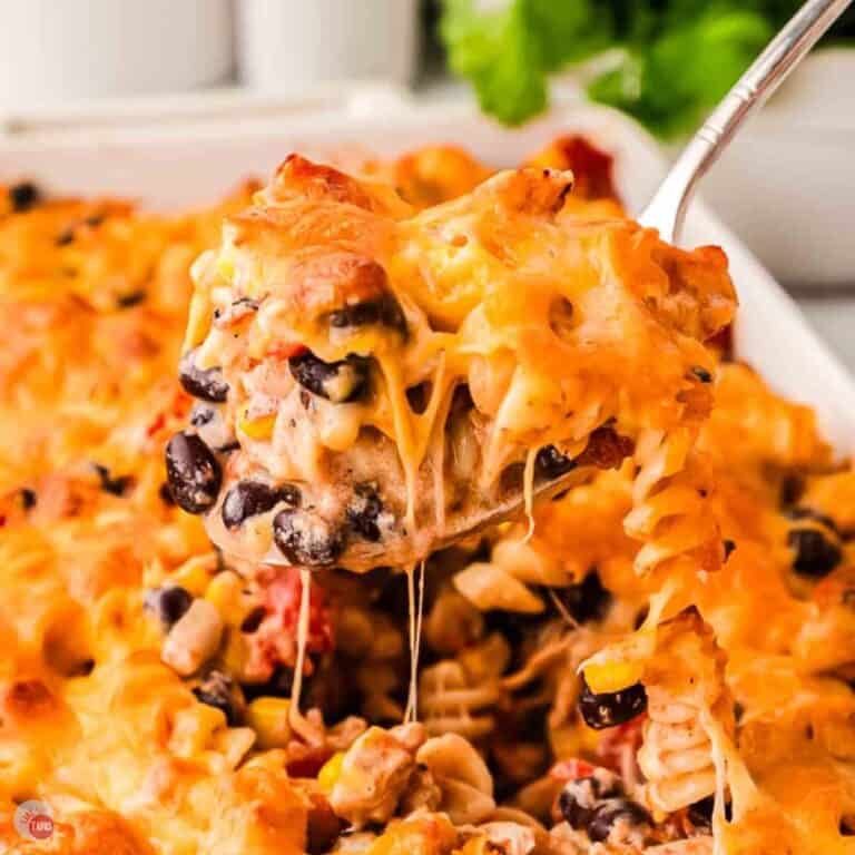 Spoonful of fiesta chicken casserole with melted cheese stretching from the dish