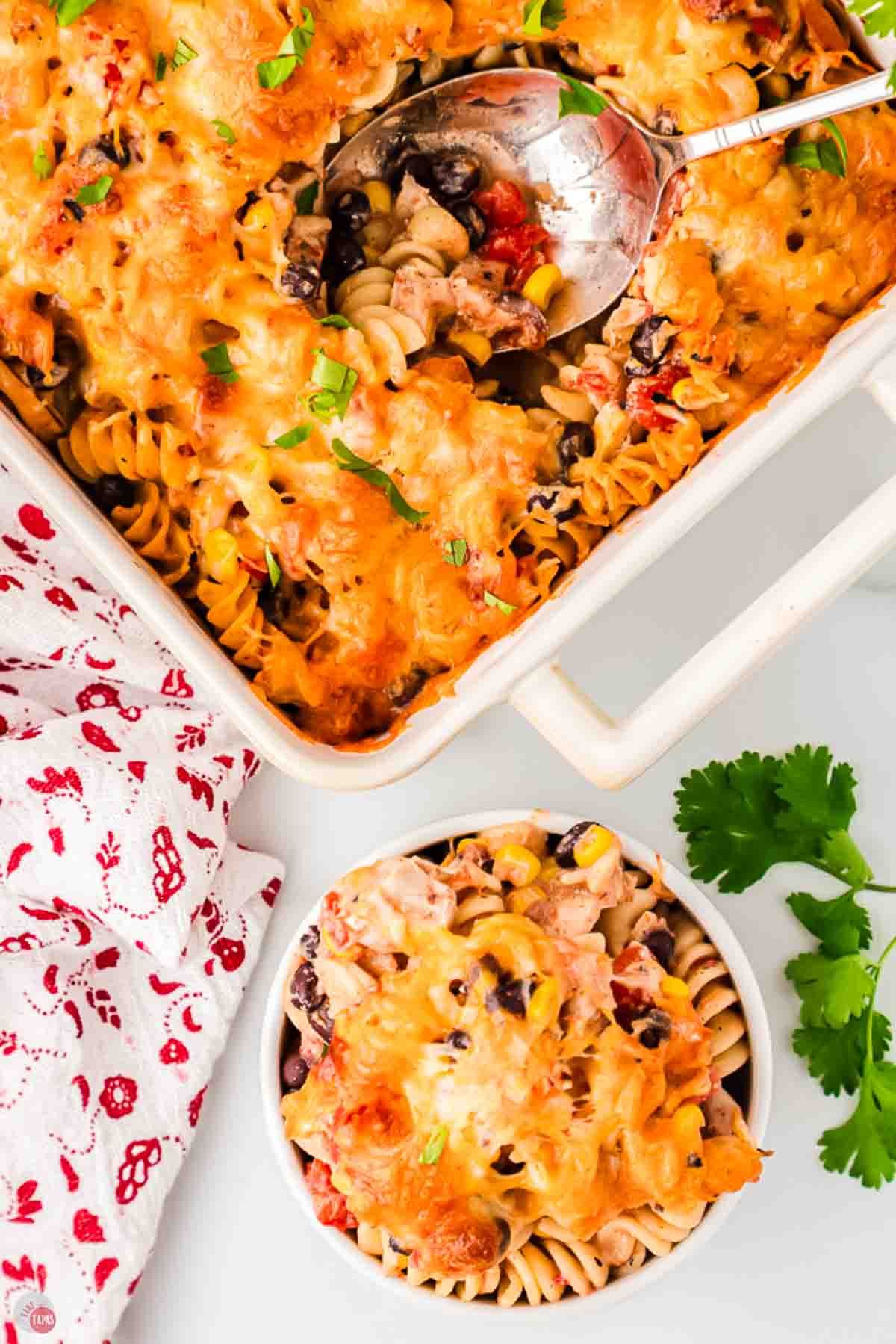 Serving spoon in a dish of fiesta chicken casserole next to a filled bowl