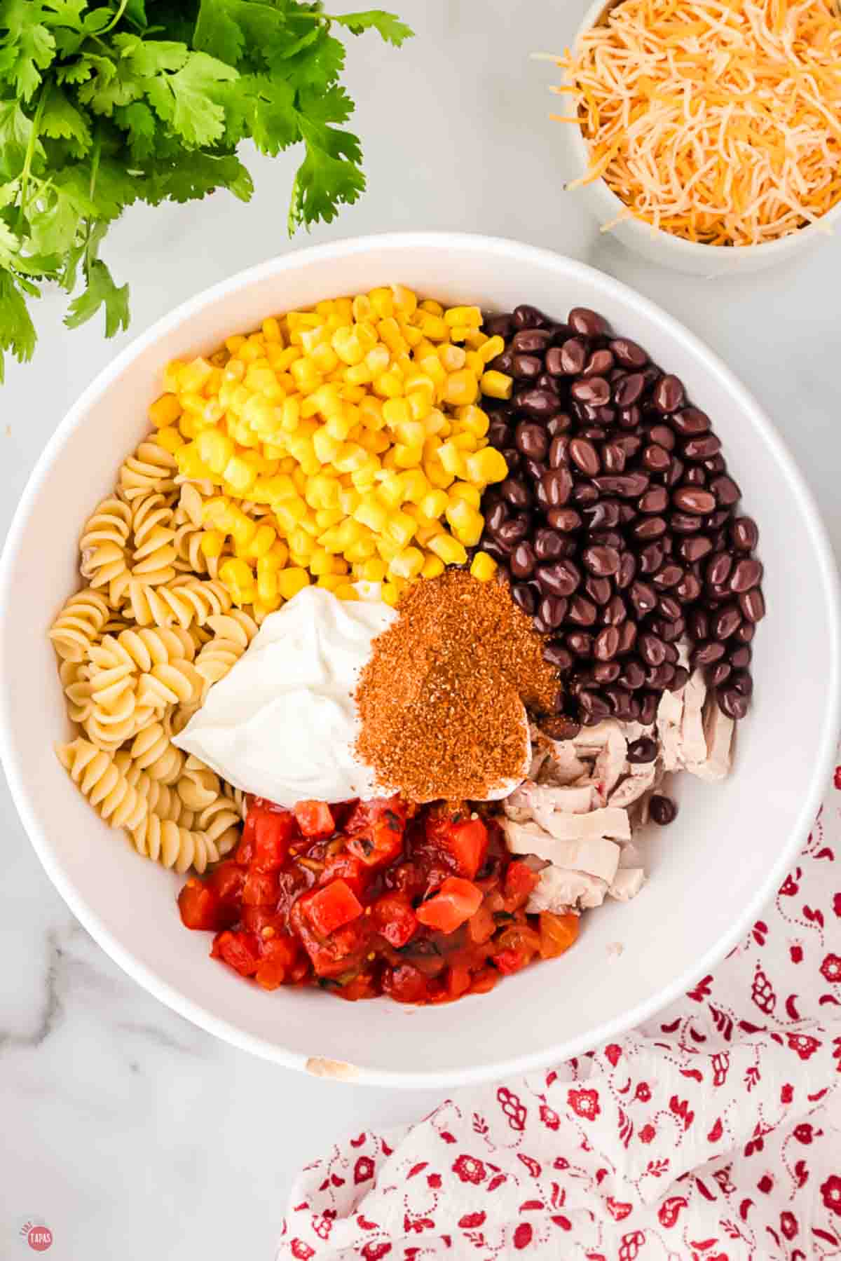 Rotini topped with corn, black beans, sour cream, taco seasoning, diced tomatoes and chicken before mixing