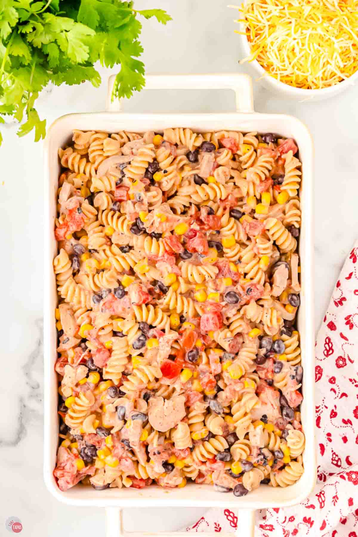 Unbaked fiesta chicken casserole spread in a white 9x13 baking dish