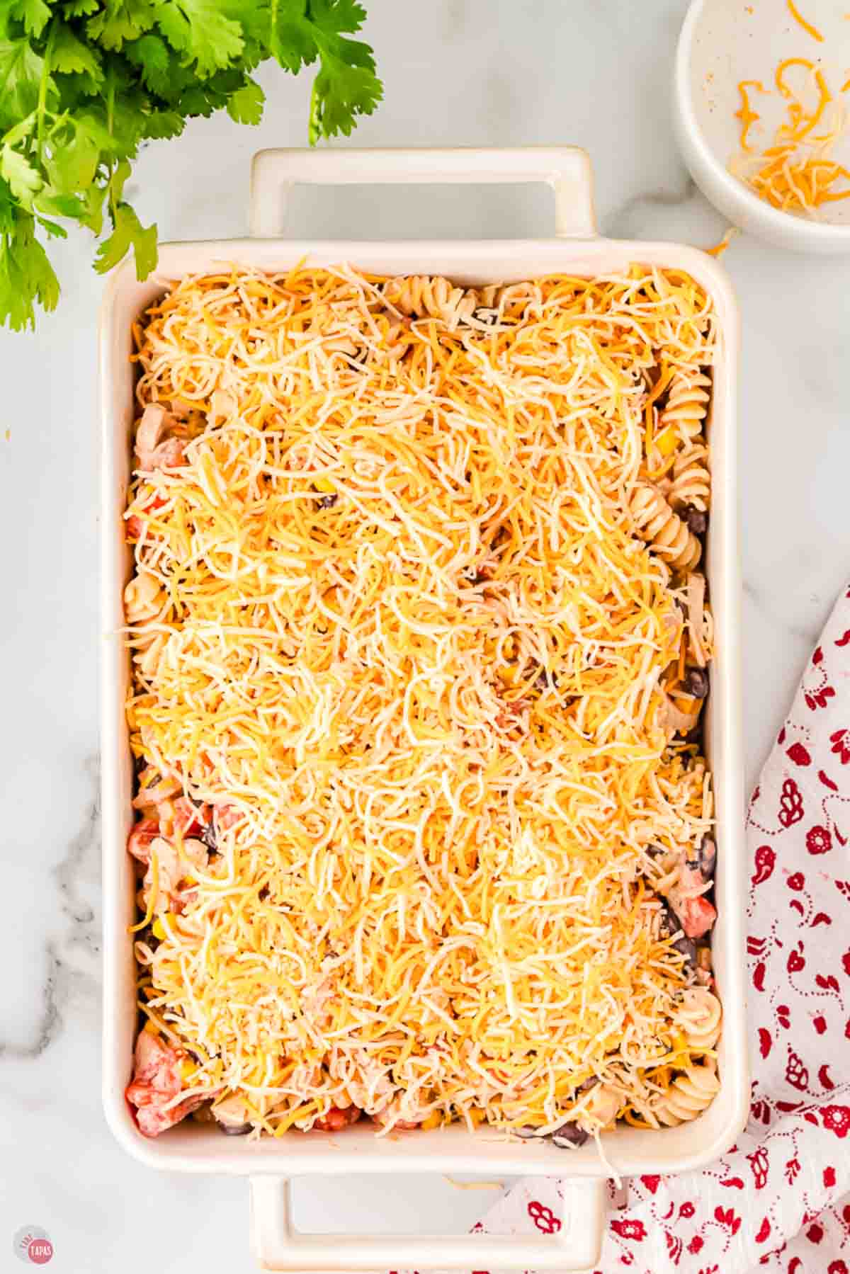 Shredded Mexican blend cheese sprinkled over the unbaked casserole