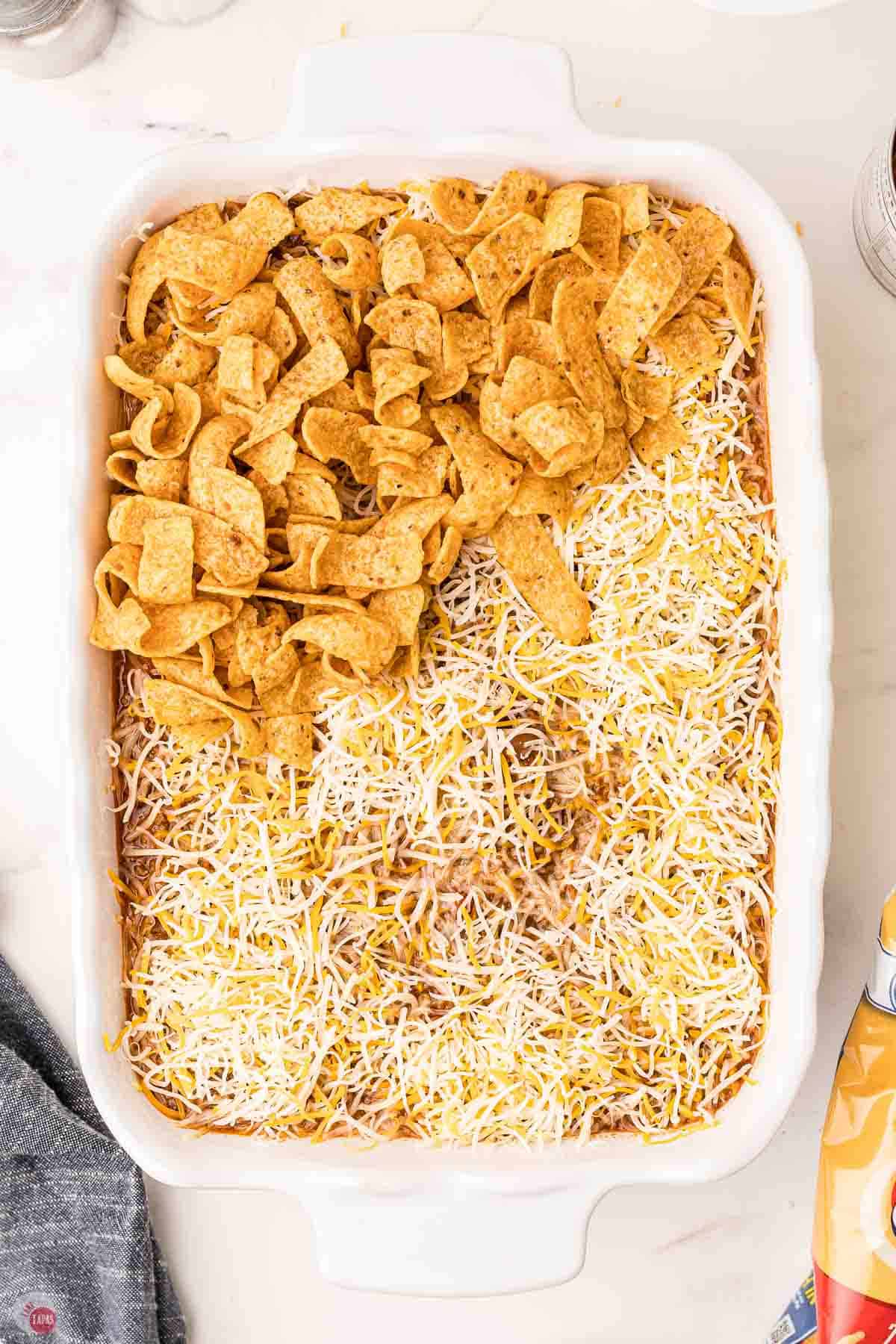 casserole dish partially covered in cheese and frito corn chips