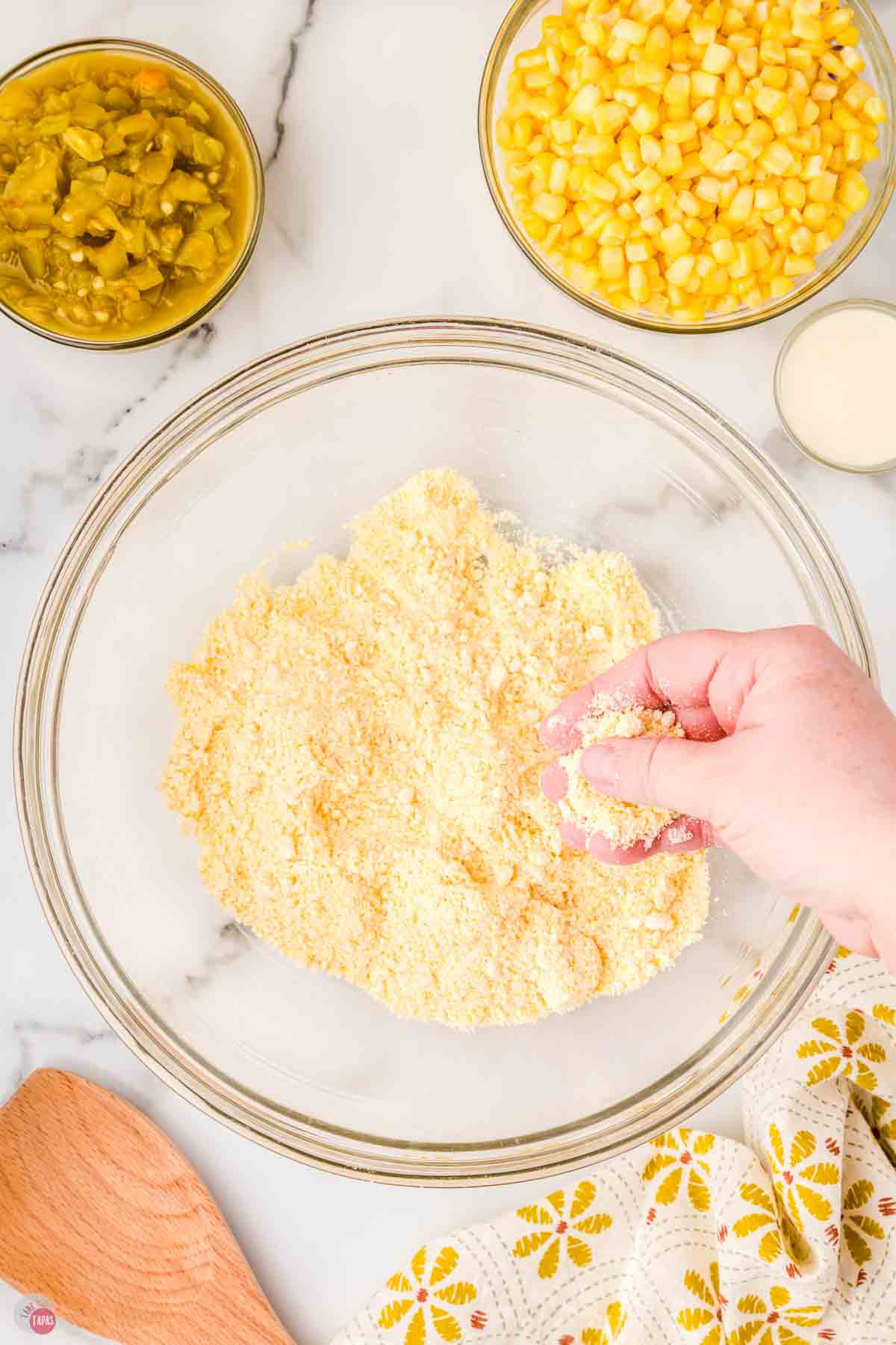 hand separating cornmeal mix in a clear mixing bowl