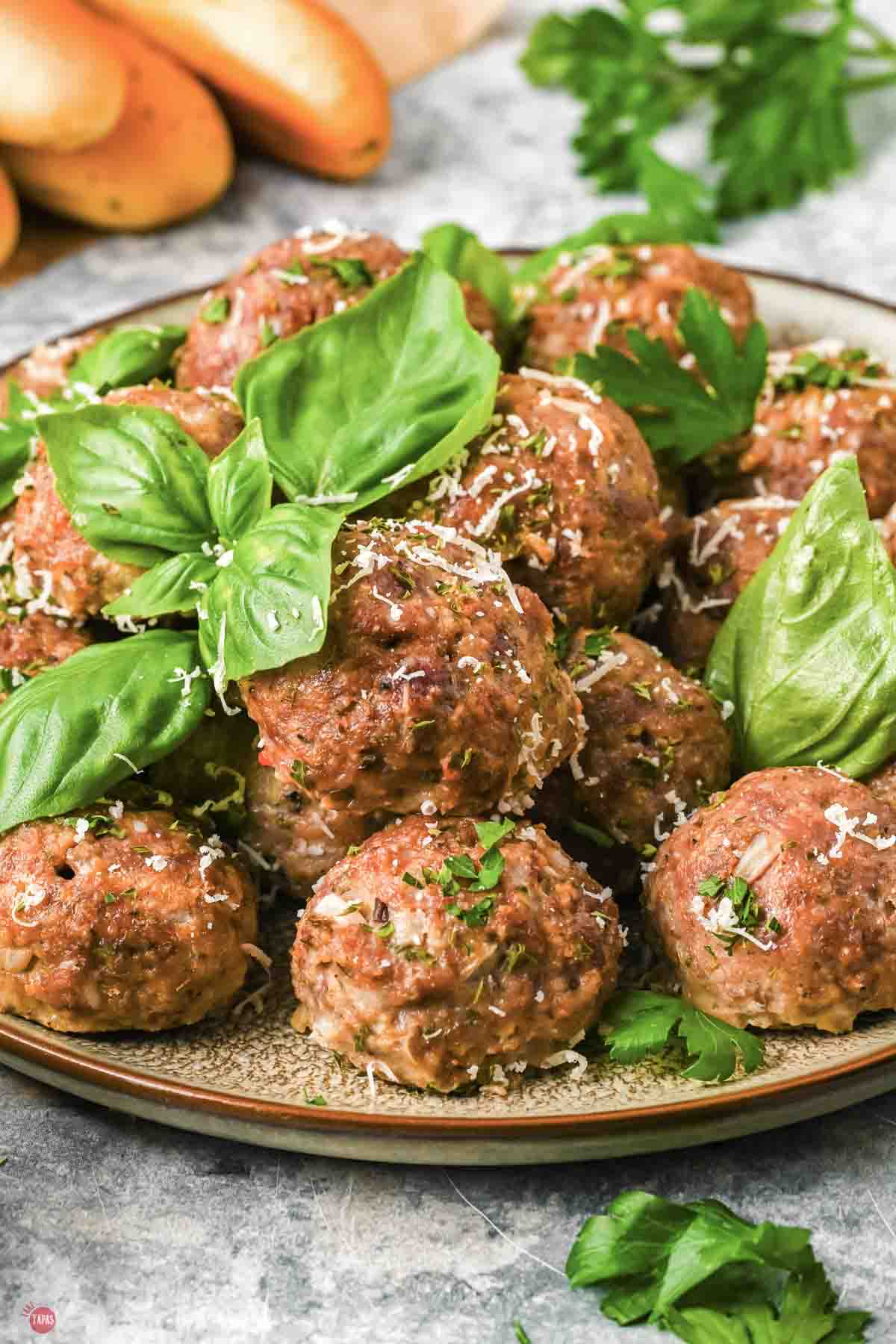 close up of meatballs on a plate topped with fresh basil