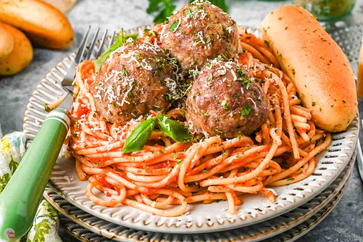 three Italian meatballs on a plate of spaghetti