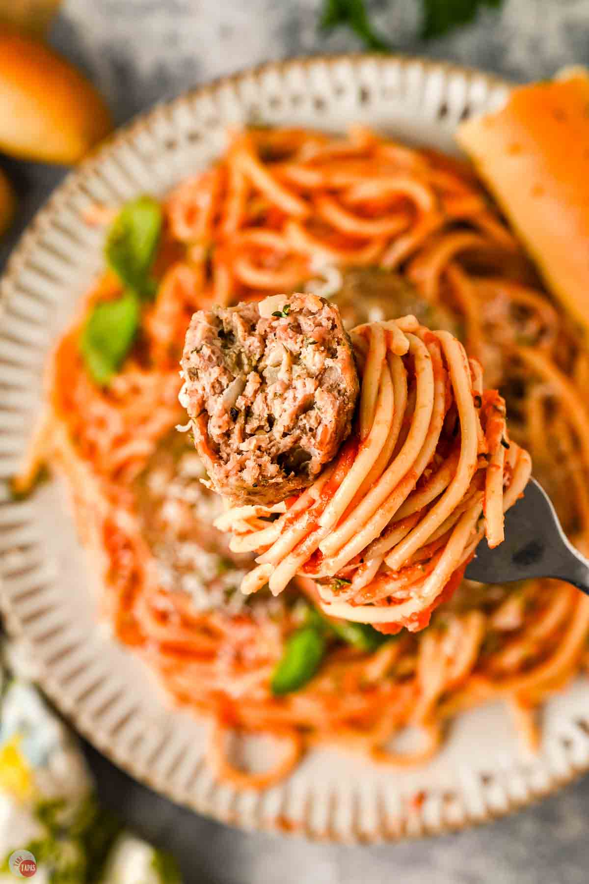 fork with spaghetti and a meatball with a bite taken out of it