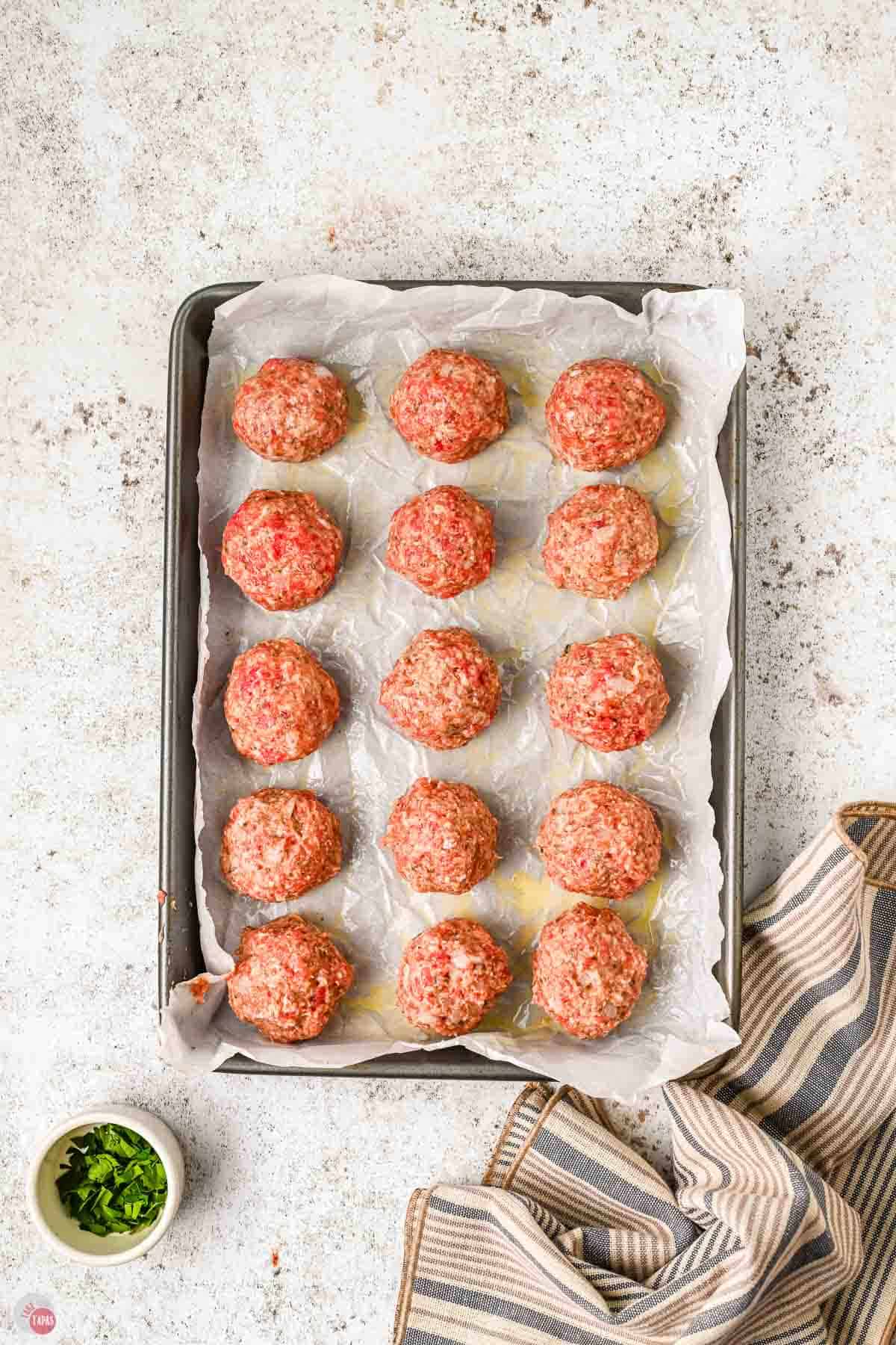 unbaked meatballs on a lined baking sheet