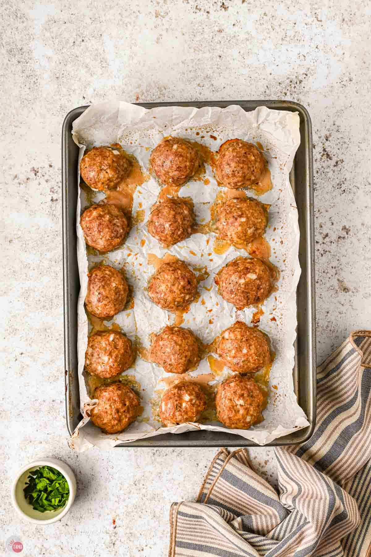 baked meatballs on a parchment lined baking sheet