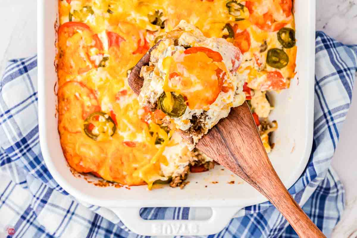 casserole with a wood spoon scooping out a portion