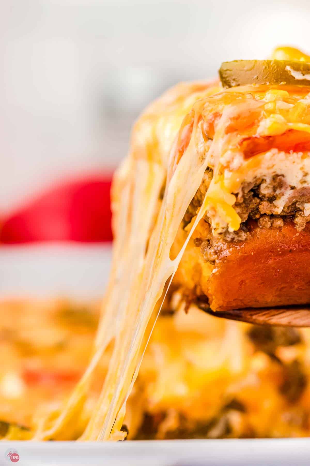 slice of casserole being pulled out if a dish with cheese stretching