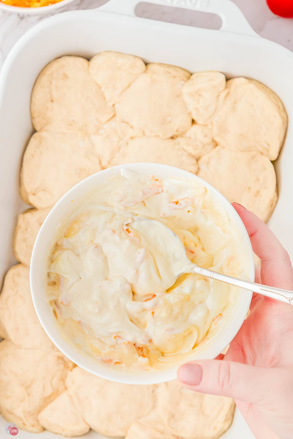 baking sheet with a biscuit crust and a small bowl of mayo and sour cream mixed together