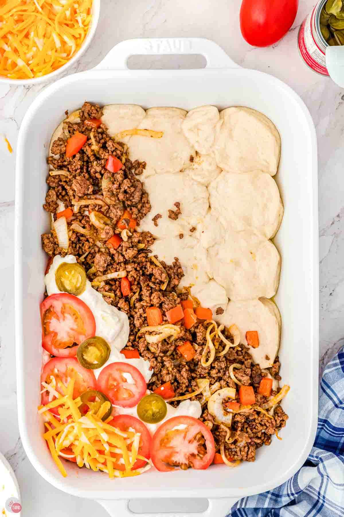 baking dish with diagonal layers of biscuits, ground beef, and sliced tomatoes