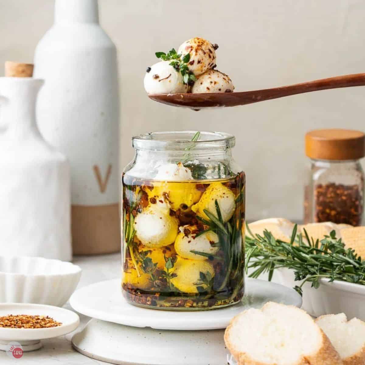 jar of marinated mozzarella balls with a spoon scooping a few out