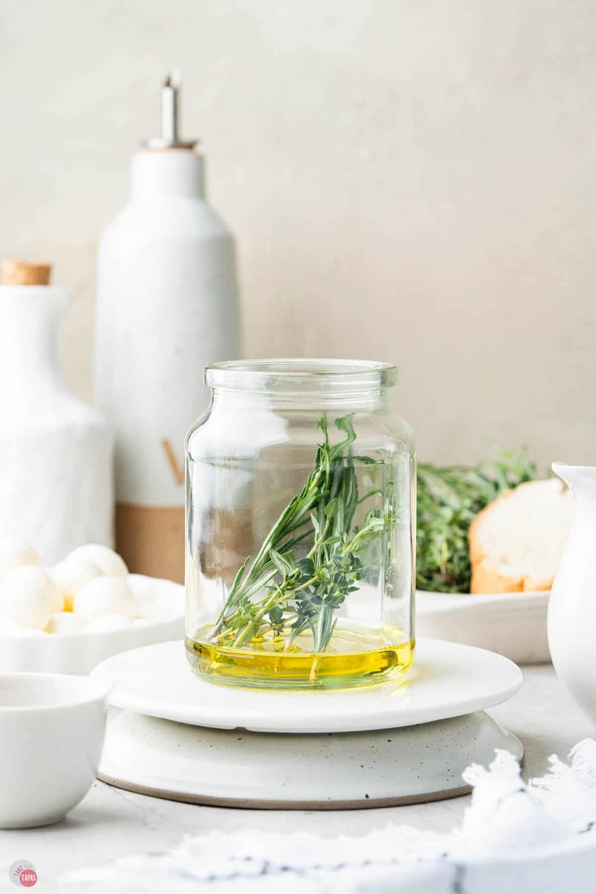 jar on a plate with a small amount of olive oil and a sprig of rosemary
