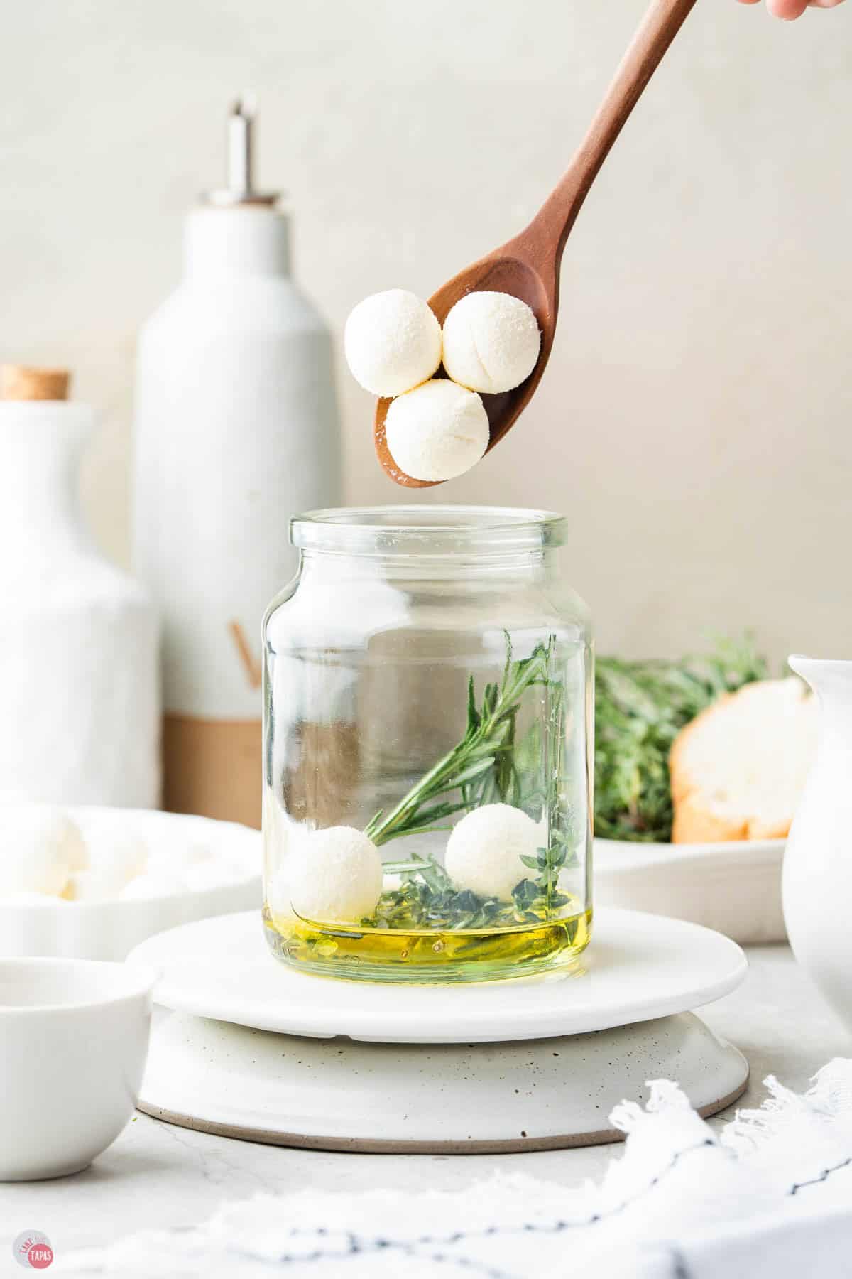 mozzarella balls being added to a jar