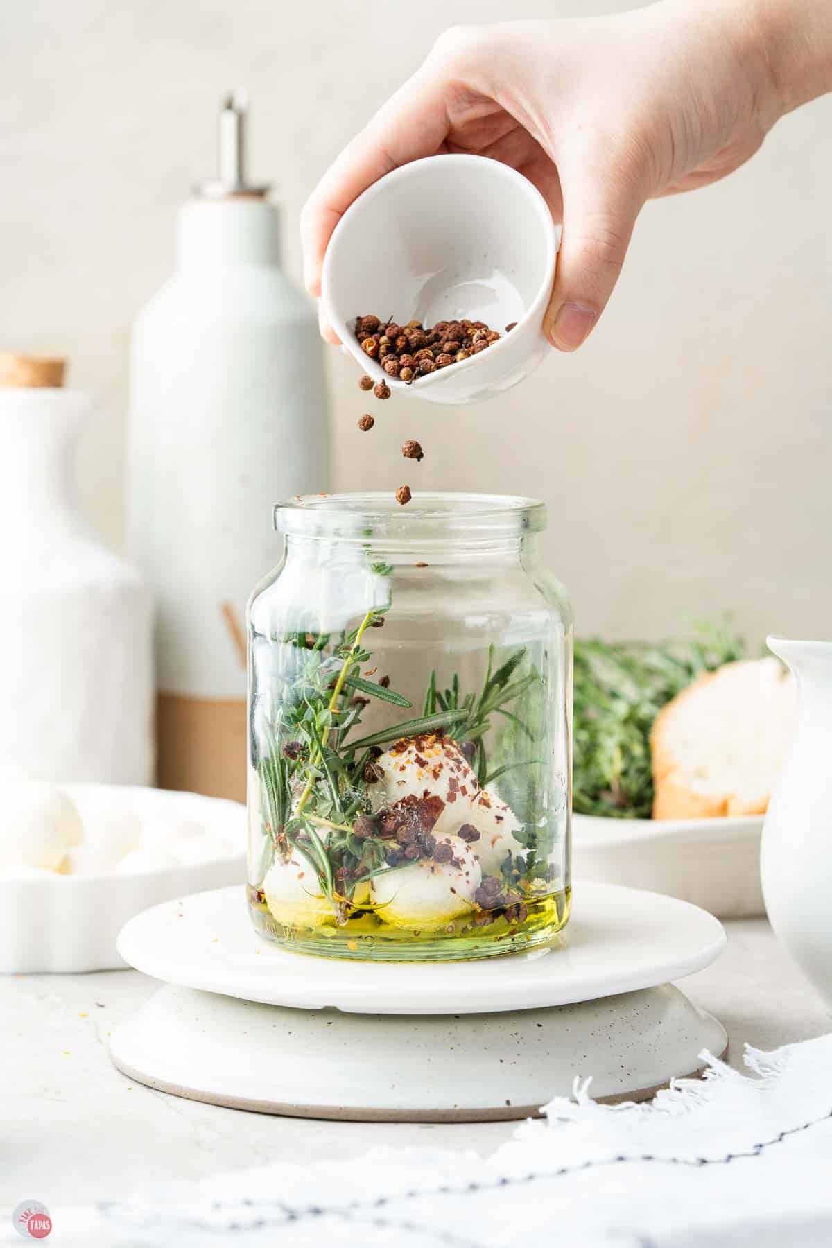 jar of rosemary and olive oil with mozzarella balls