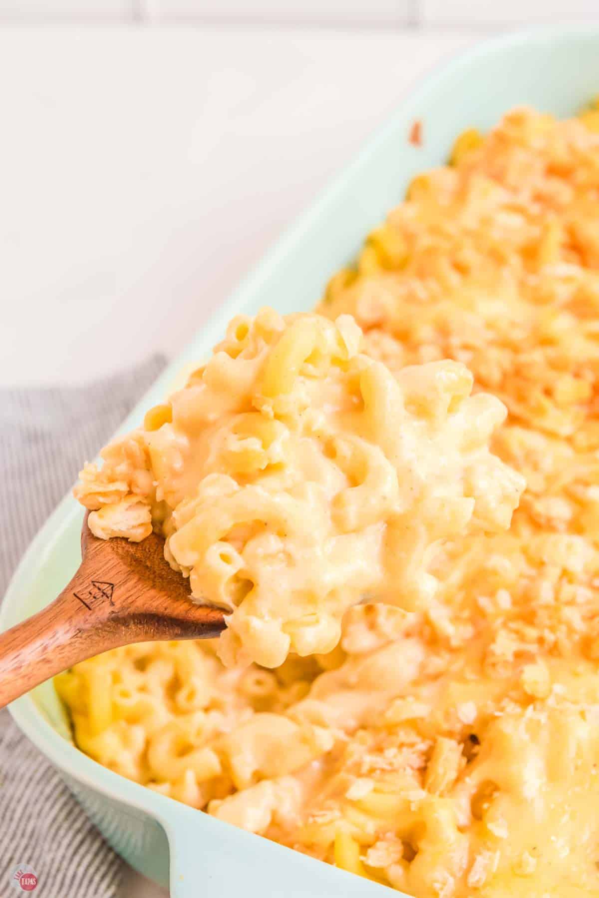spoon scooping baked mac and cheese out of a casserole dish