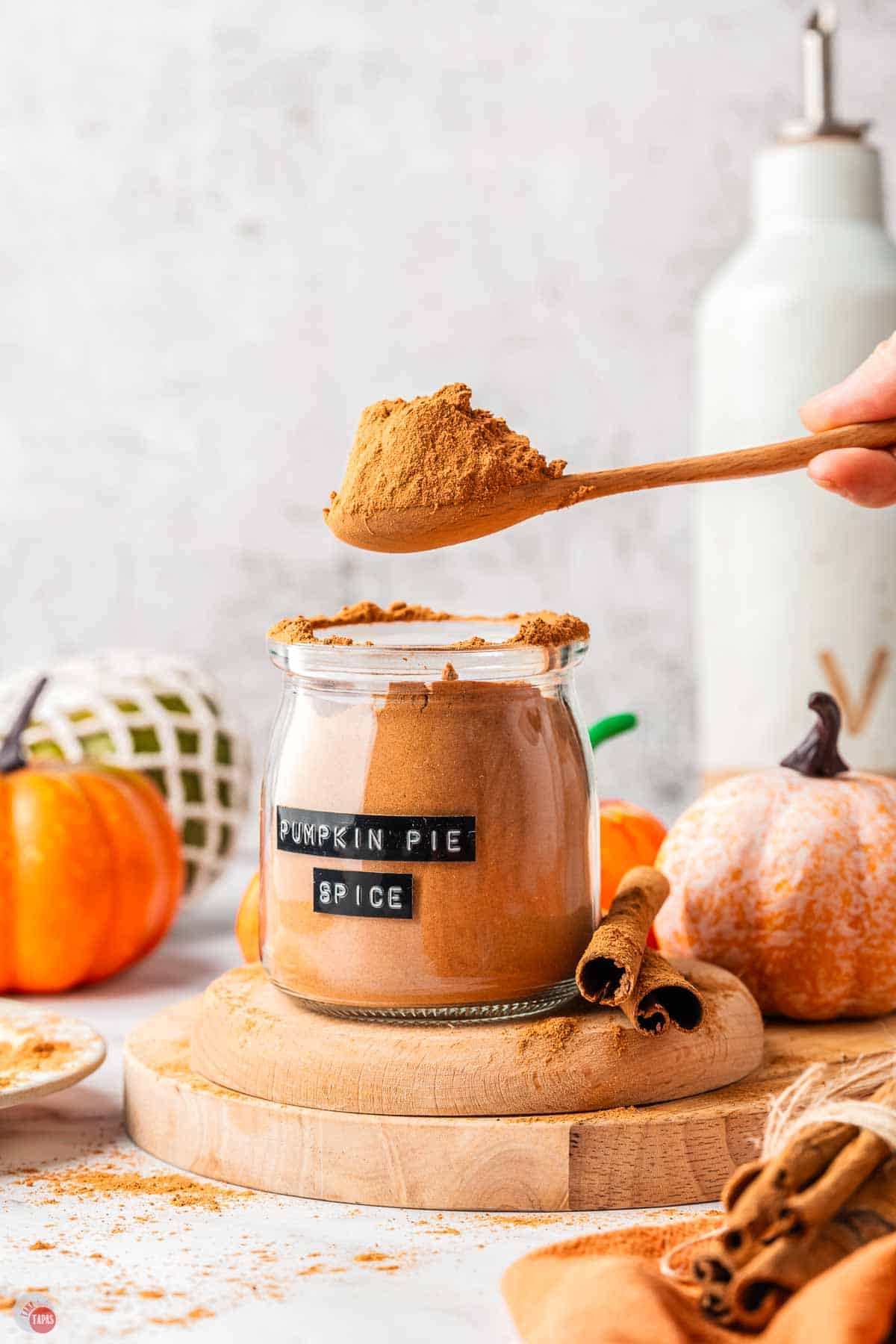 large wood spoon scooping some pumpkin pie spice out of a jar