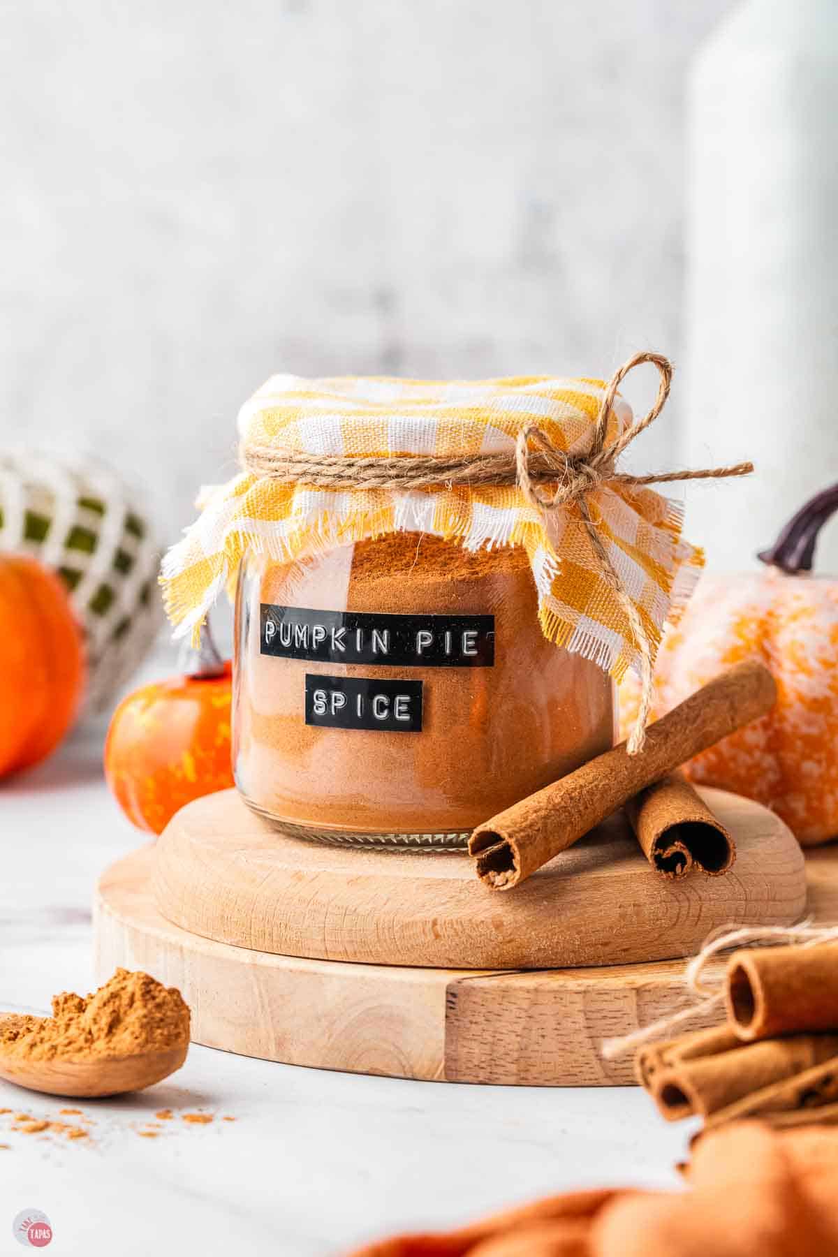 covered jar of pumpkin pie spice with cinnamon sticks next to it