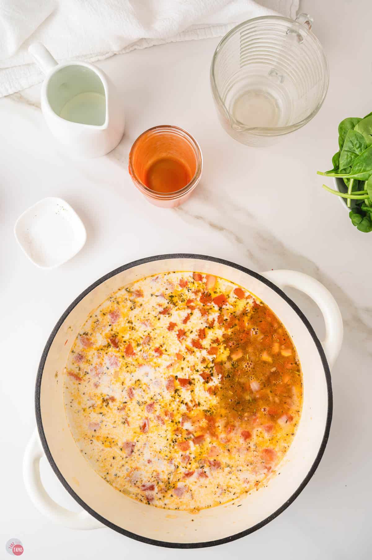 Broth, heavy cream and tomato sauce just poured into the pot over the sauteed vegetables for ravioli soup