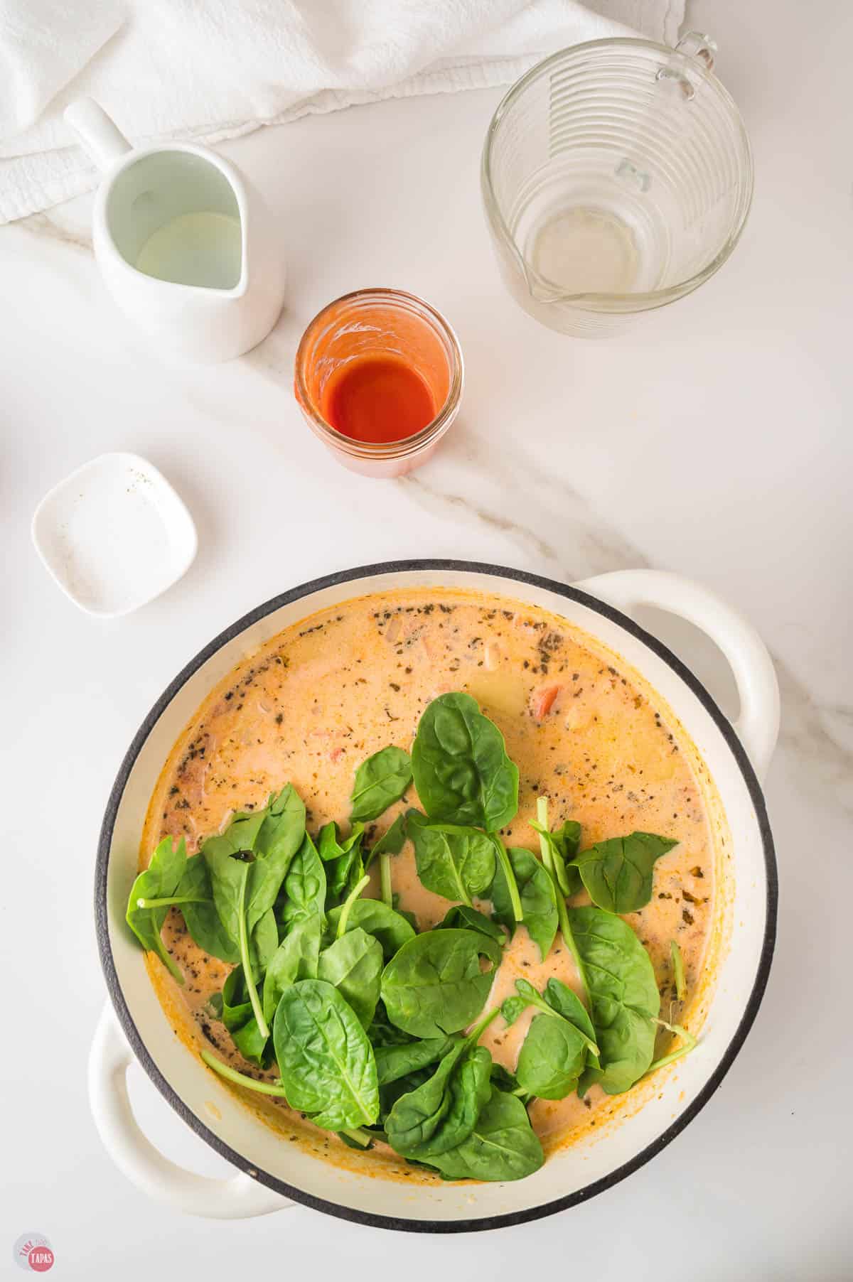 Fresh spinach leaves added on top of the ravioli soup in the pot before they wilt
