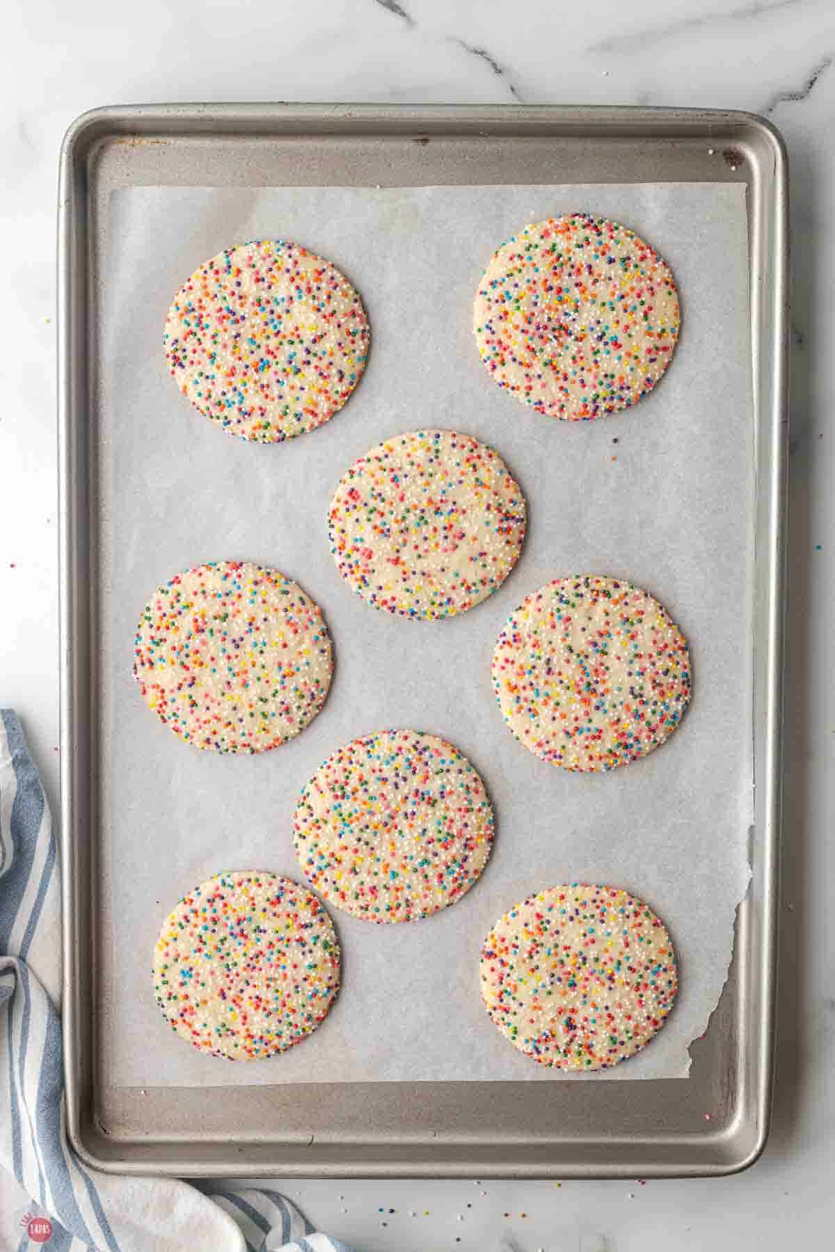 baked sprinkle cookies cooling on a baking sheet
